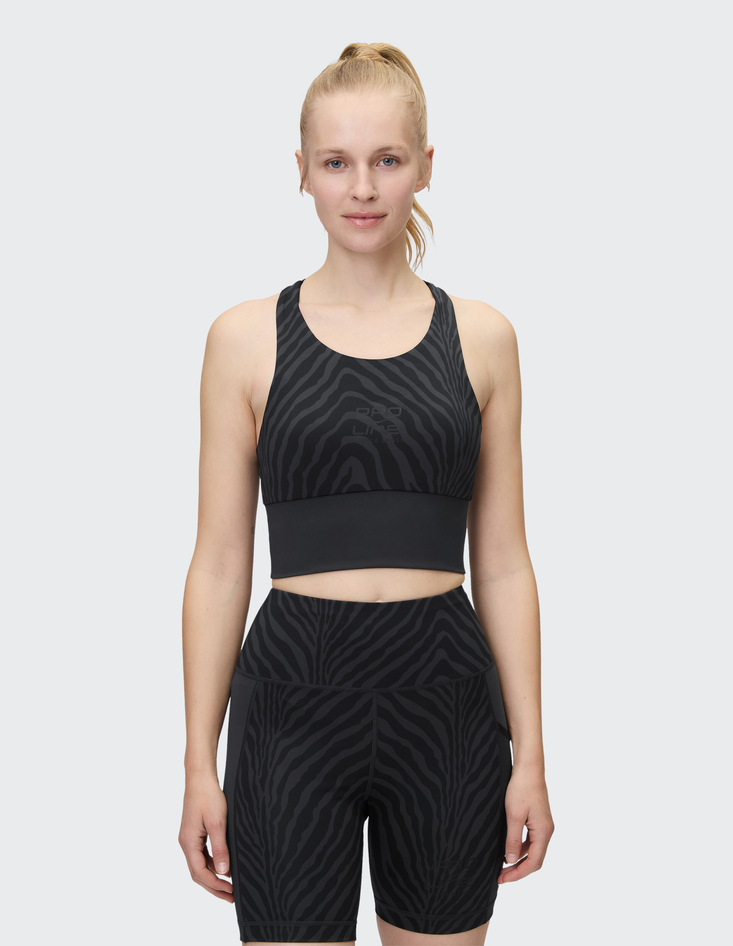 Frau trägt einen schwarzen Venice Beach Top Buffalo Sport-BH mit dezentem Animal-Print-Muster.