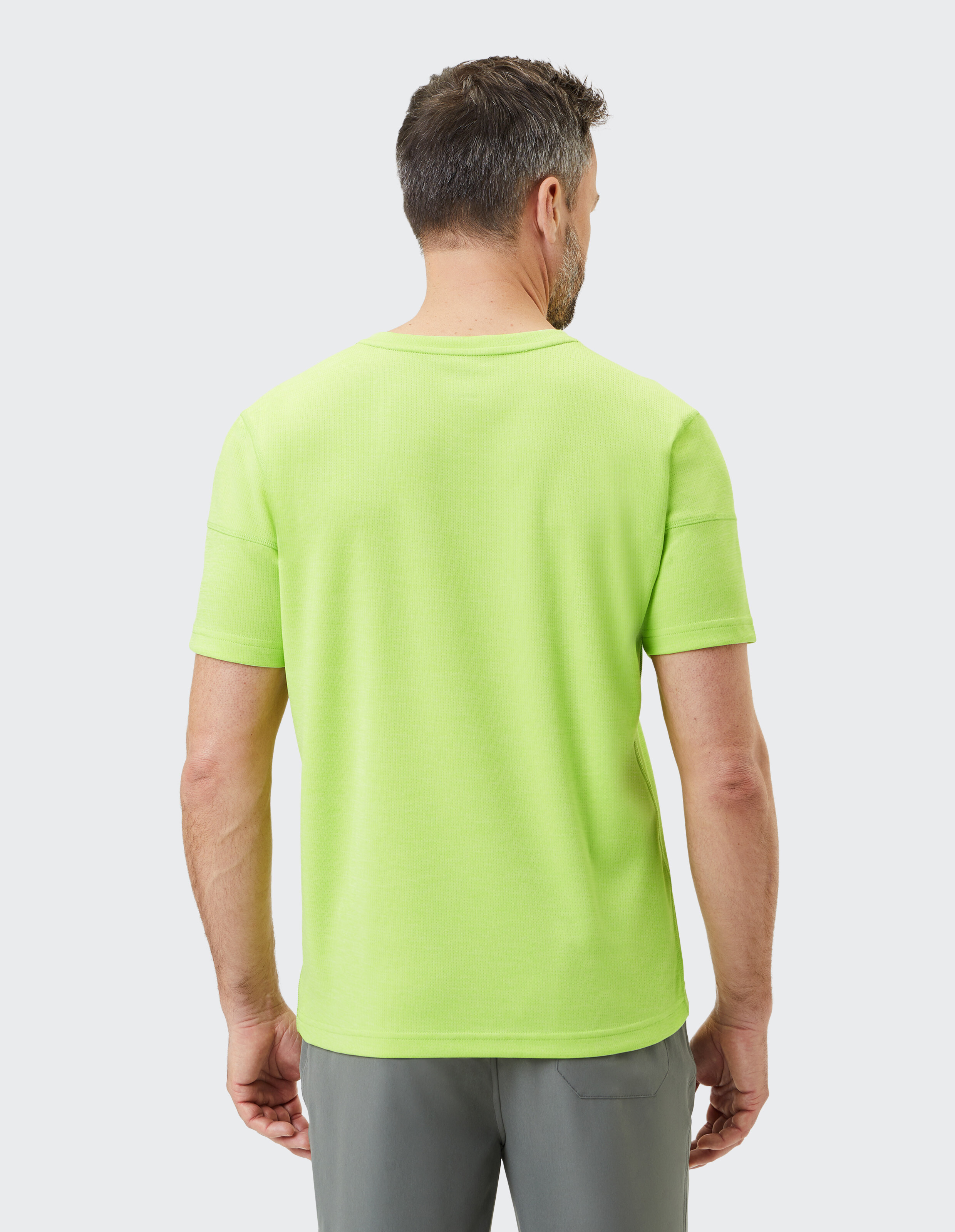 Mann trägt ein leuchtend lindgrünes Freizeit-T-Shirt, Rückansicht, Studioaufnahme.