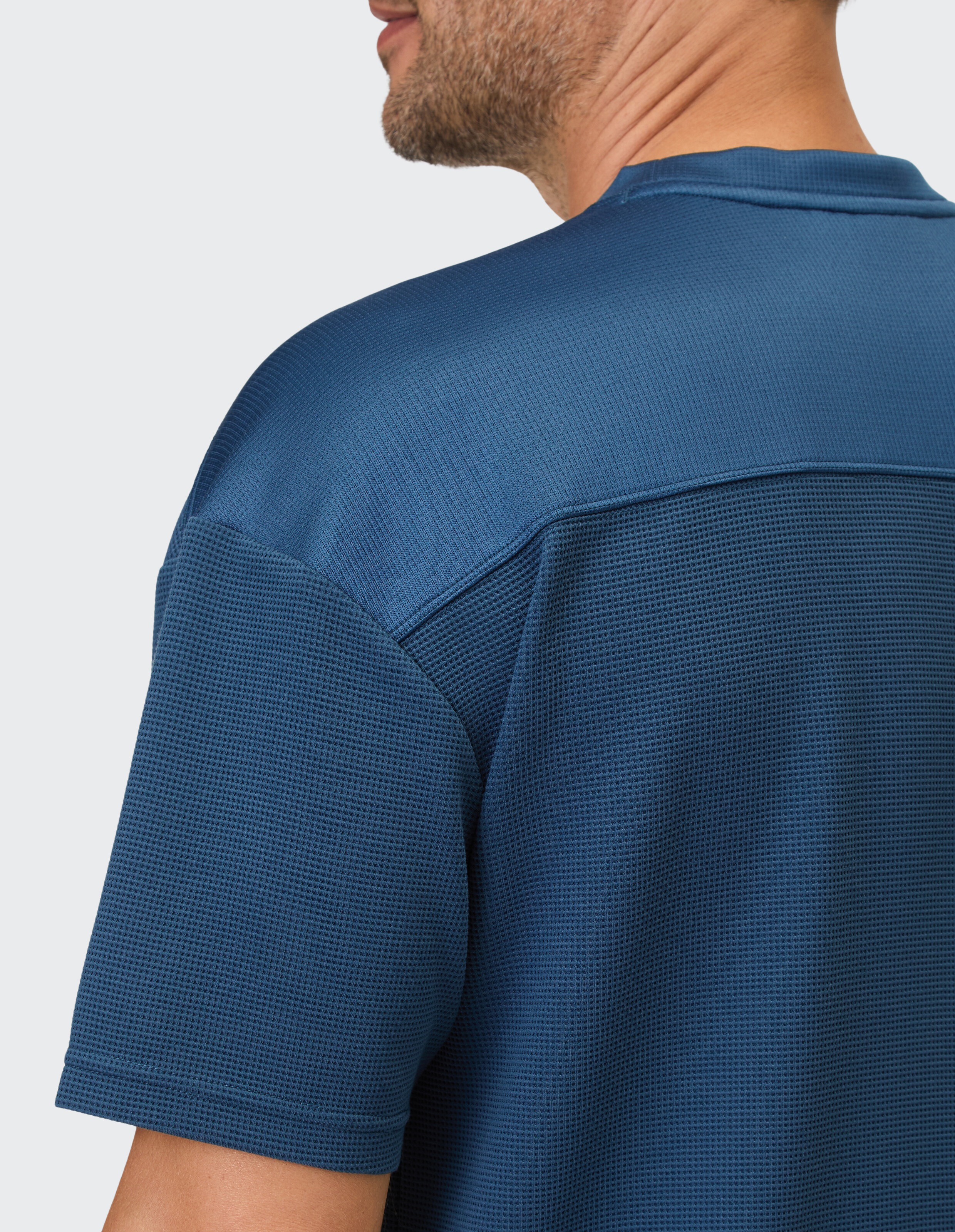Blaues Polo-Shirt mit Waffelstruktur und einer horizontalen Passe über den Schultern.