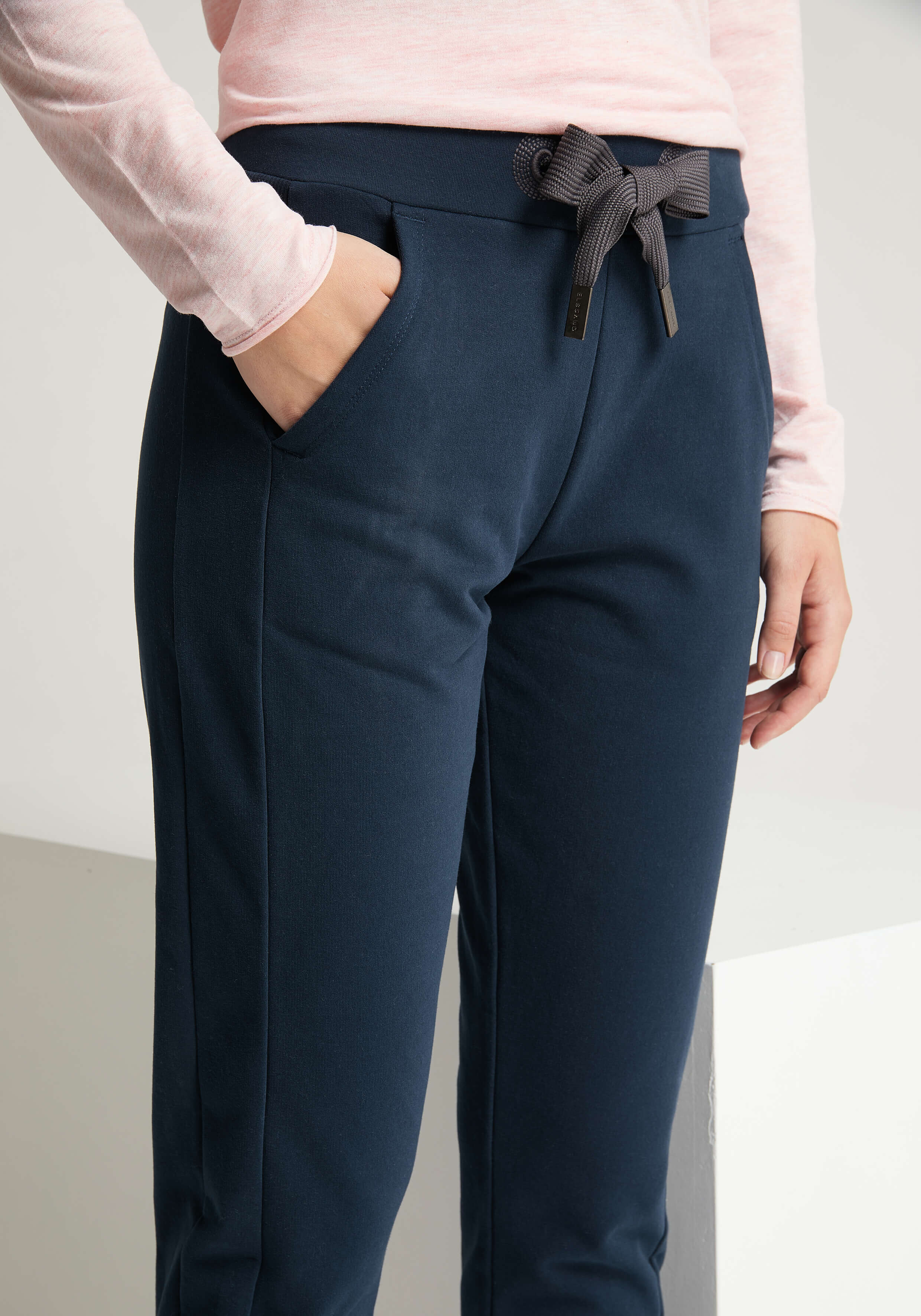 Frau trägt dunkelblaue, lässige Lounge-Hose mit Kordelzug in der Taille und Taschen.