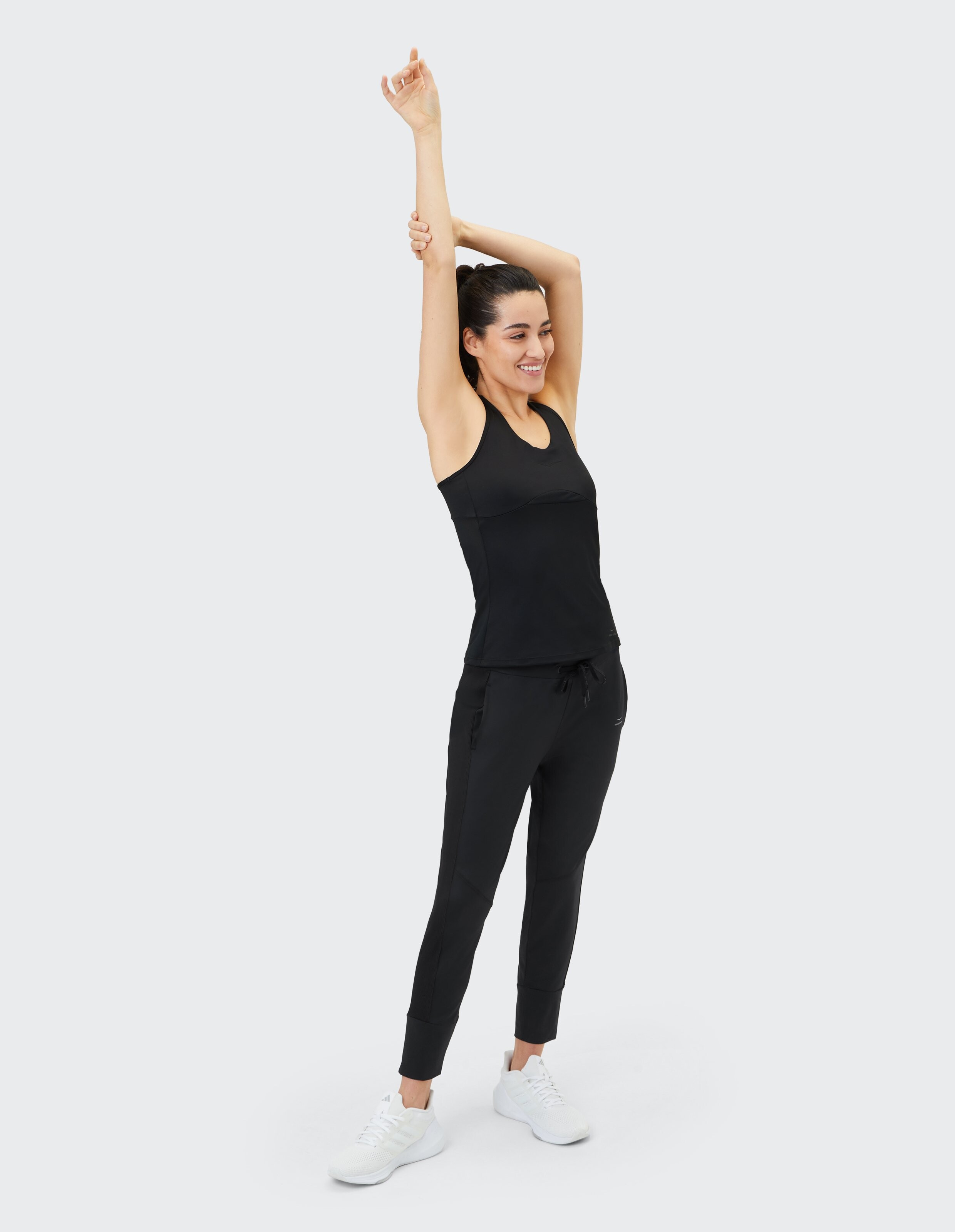 Frau trägt ein schwarzes Tanktop und passende Jogginghosen für einen gemütlichen, lässigen Look.