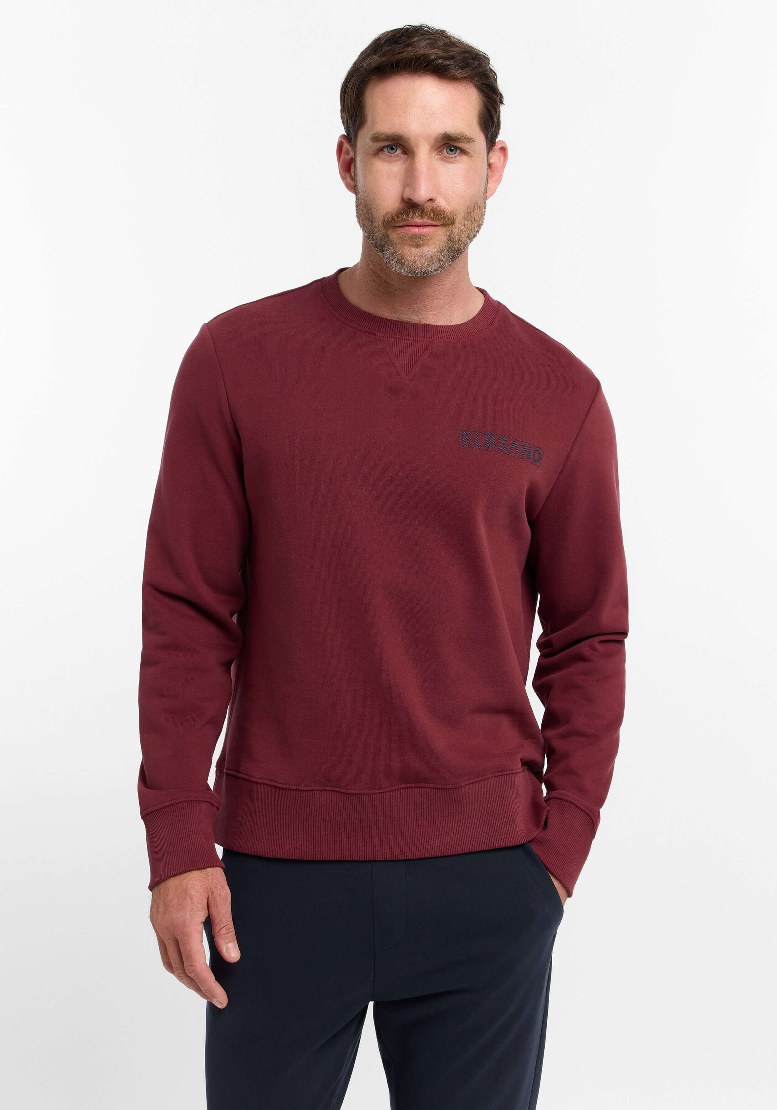 Mann trägt ein gemütliches burgunderrotes ELBSAND-Sweatshirt mit Rundhalsausschnitt für einen lässigen Alltagsstil.