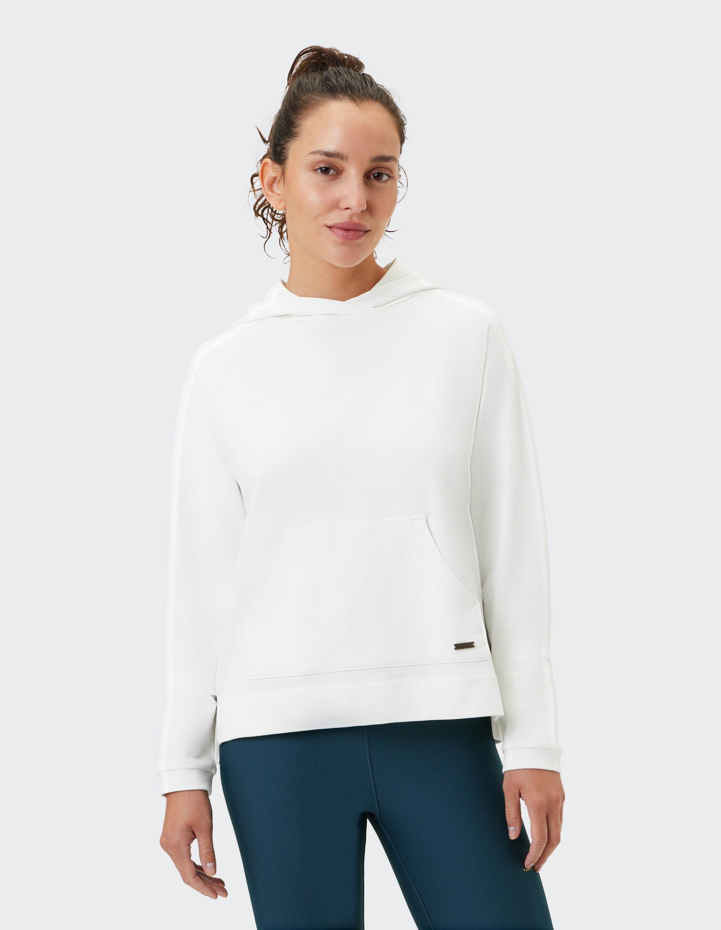 Frau trägt einen kuscheligen weißen ELBSAND-Hoodie mit Vordertasche für lässige Lounge-Kleidung.