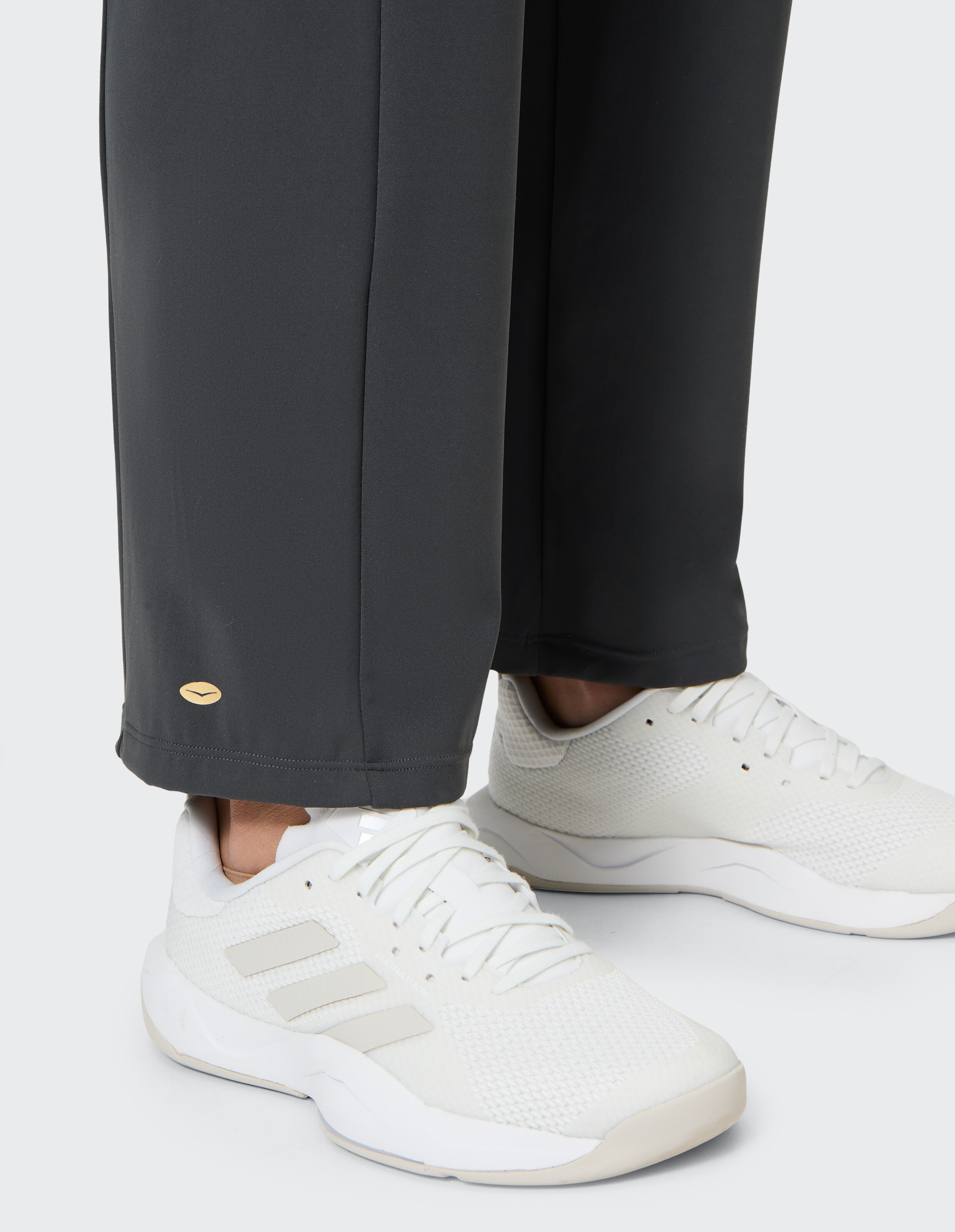 Nahaufnahme einer grauen Freizeithose gepaart mit weißen Sportschuhen.