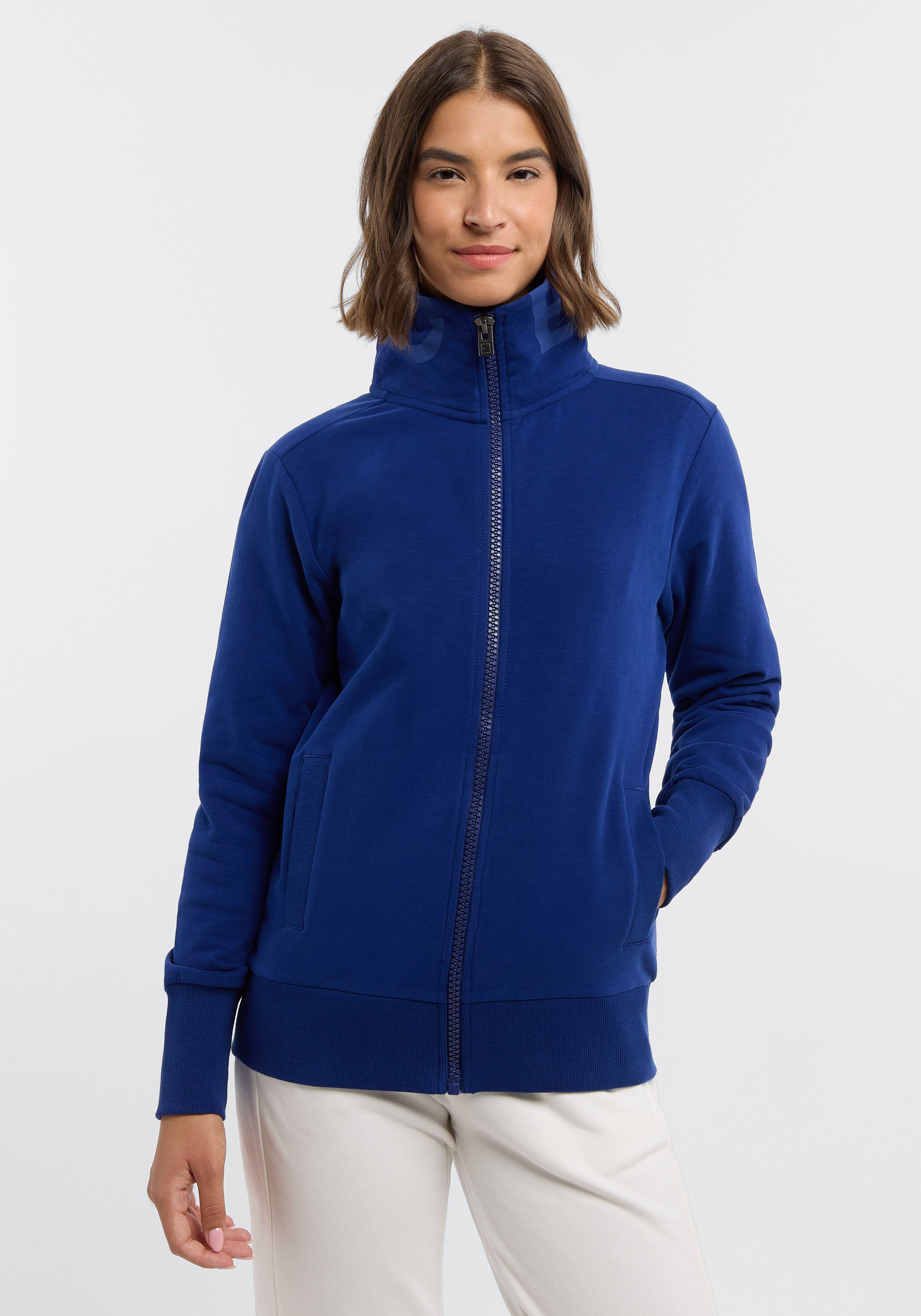 Frau trägt ein gemütliches königsblaues Sweatshirt mit Reißverschluss und hohem Kragen für lässigen Stil.