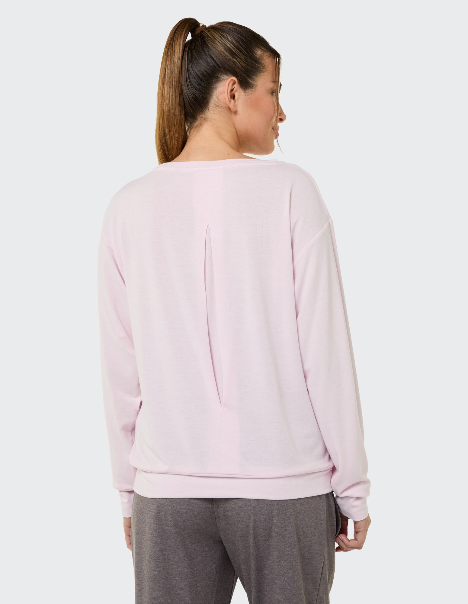 Rückansicht einer Frau in einem hellrosa lässigen Sweatshirt mit Schlitzdetail.