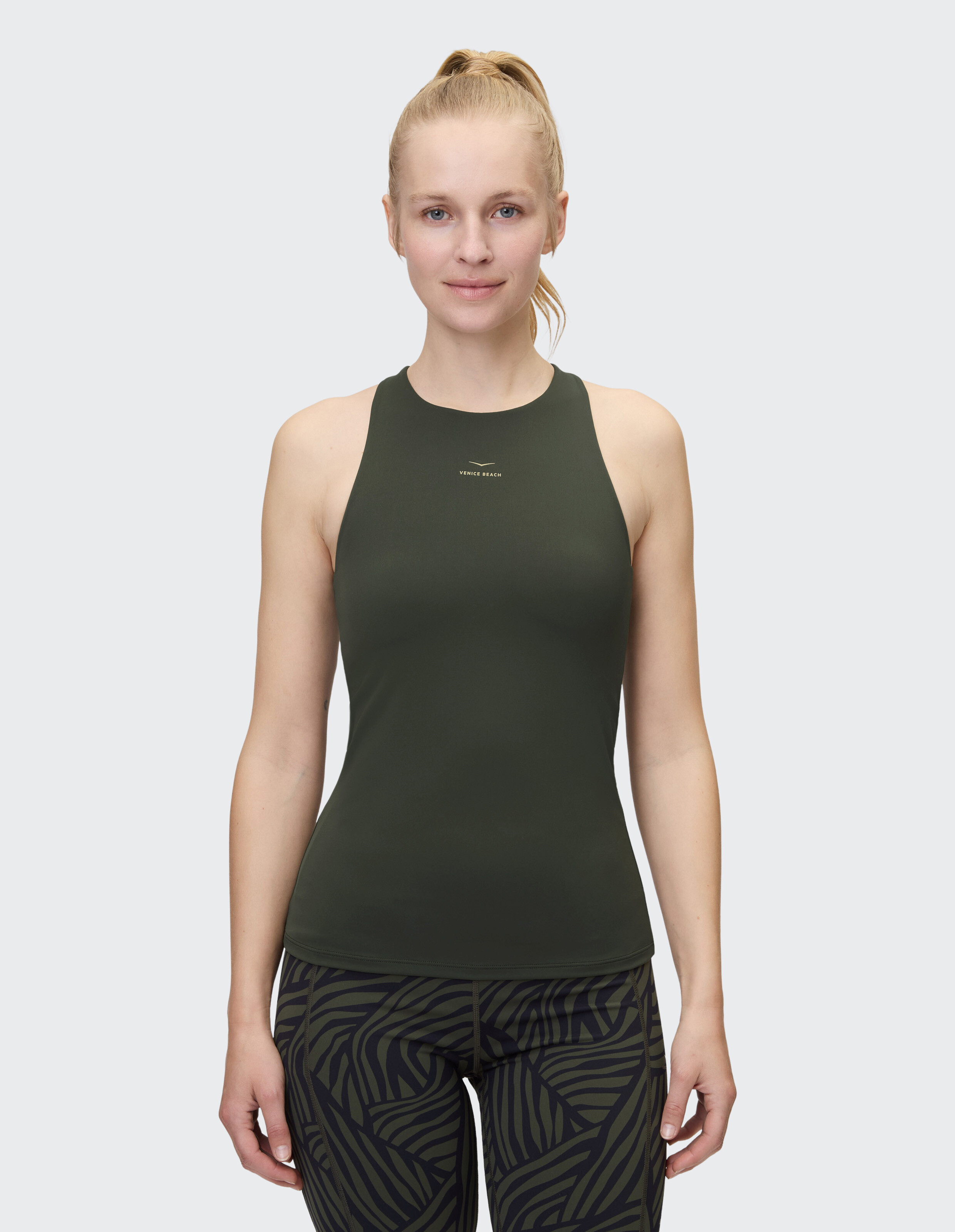 Frau trägt ein dunkelgrünes Venice Beach Virginina-Tanktop für lässige Aktivkleidung.
