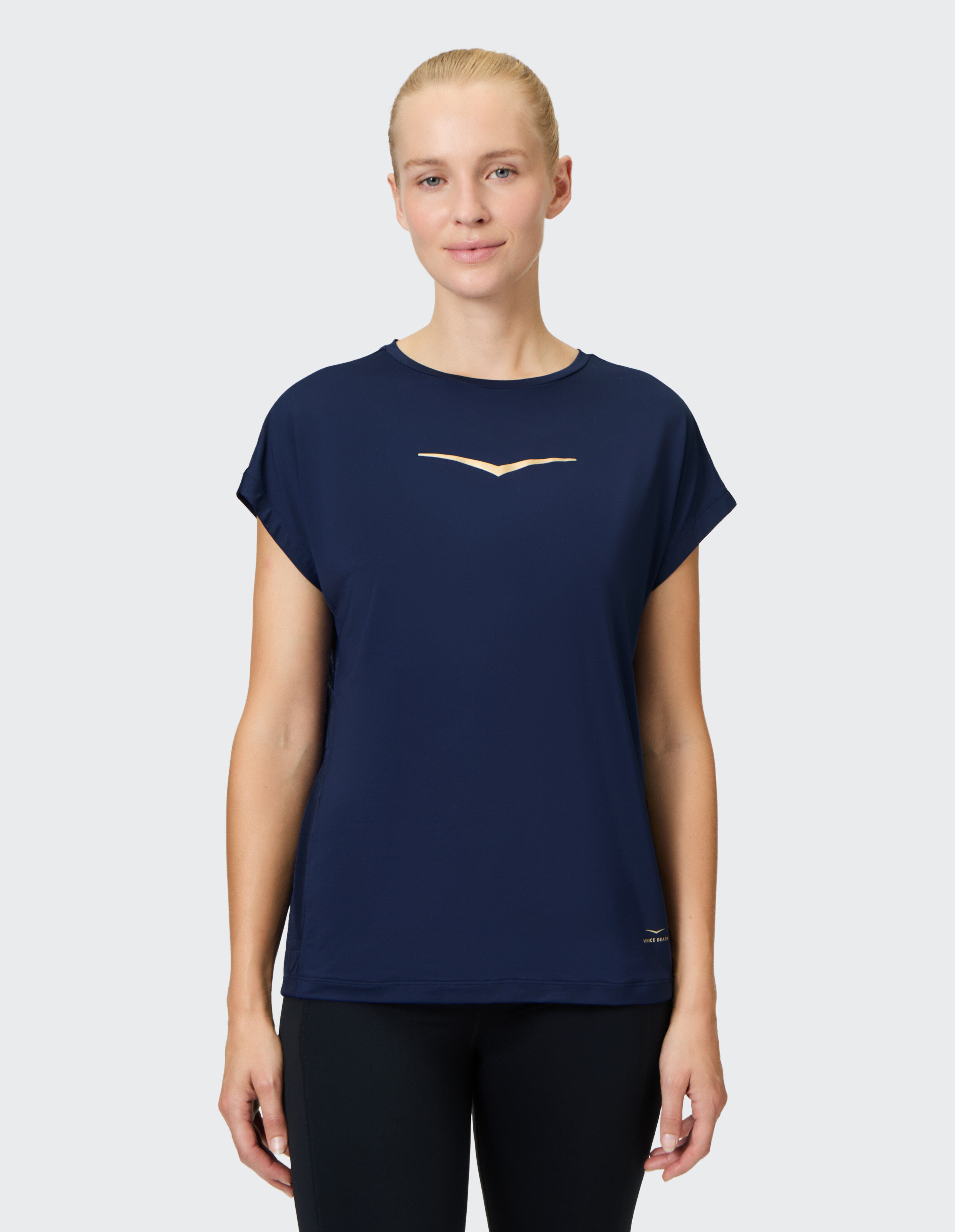 Frau trägt ein dunkelblaues kurzärmeliges Venice Beach Evie-Shirt mit goldenem Logo.