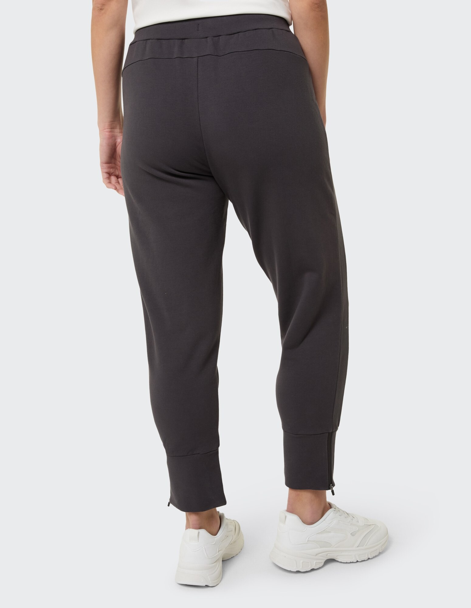 Rückansicht einer dunkelgrauen Jogginghose für Damen mit Reißverschlüssen am Knöchel und elastischem Bund.