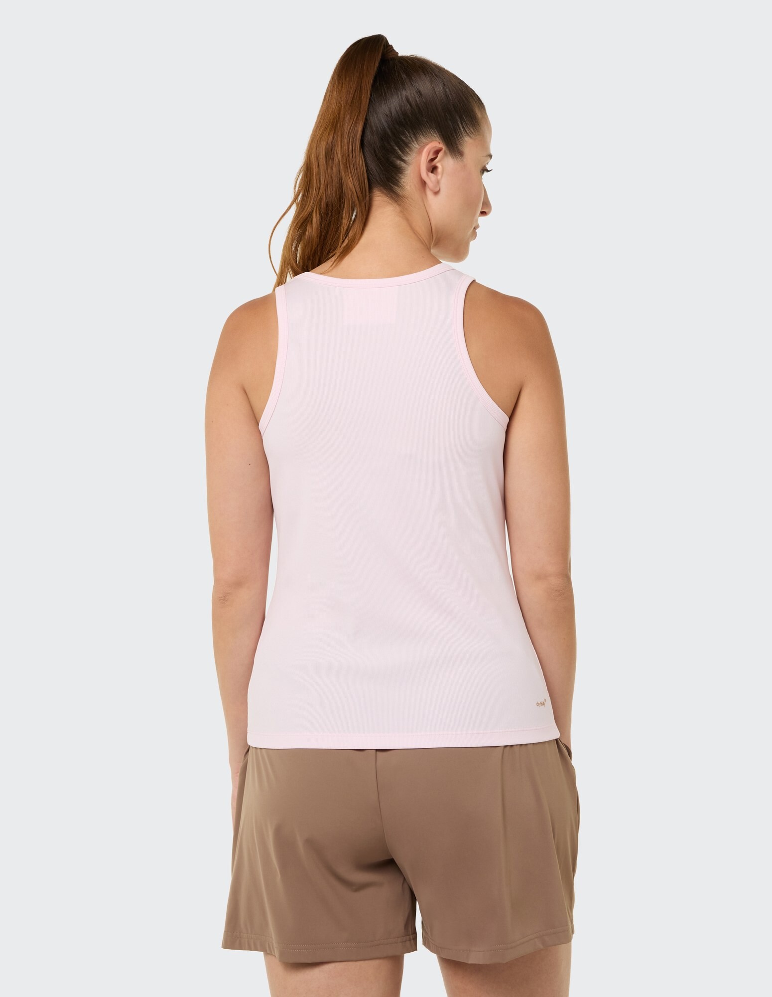 Rückansicht einer Frau in einem hellrosa Tanktop und braunen Shorts.