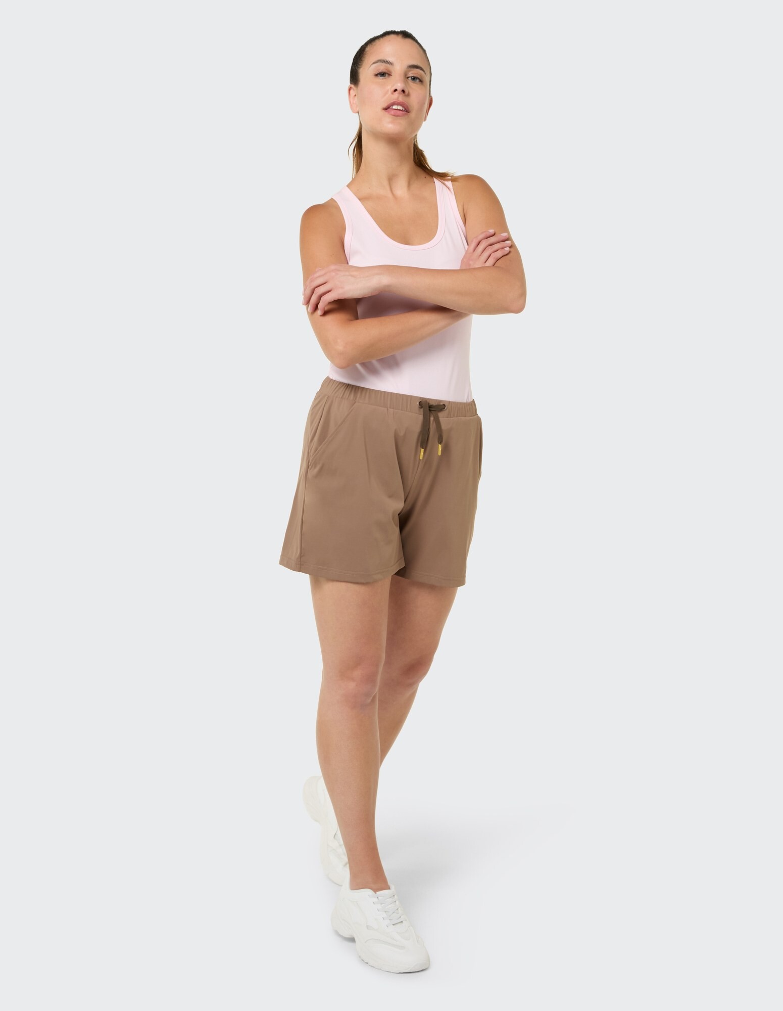 Frau in einem rosa Tanktop und braunen Shorts, die einen lässigen Sommerstil präsentiert.