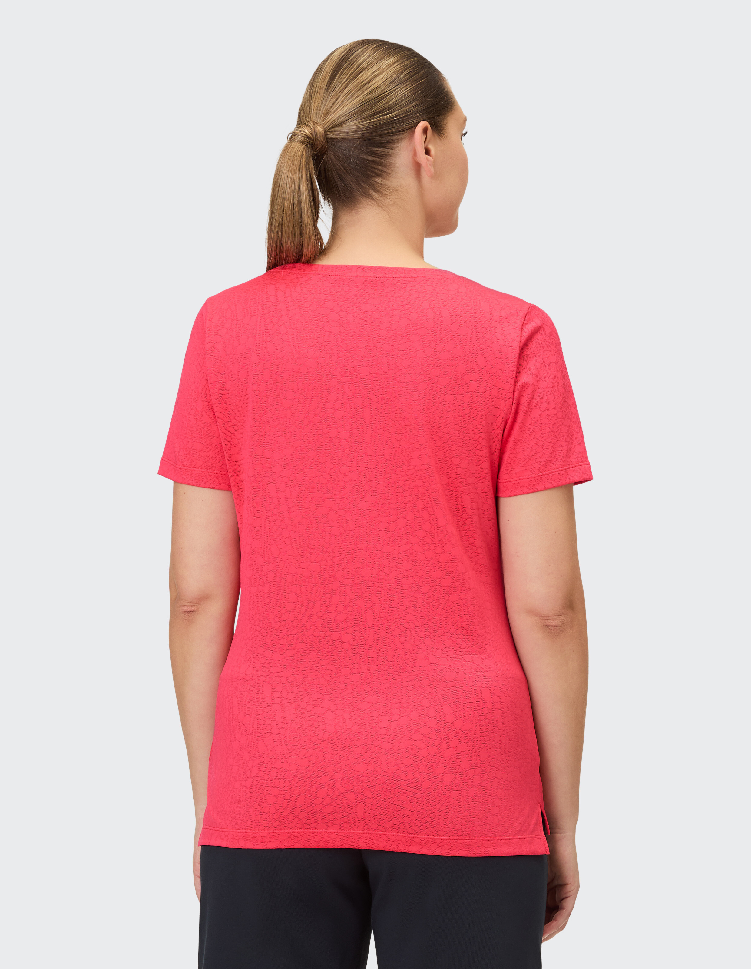 Rückansicht einer Frau, die ein leuchtend rosa lässiges T-Shirt mit Strukturmuster trägt.