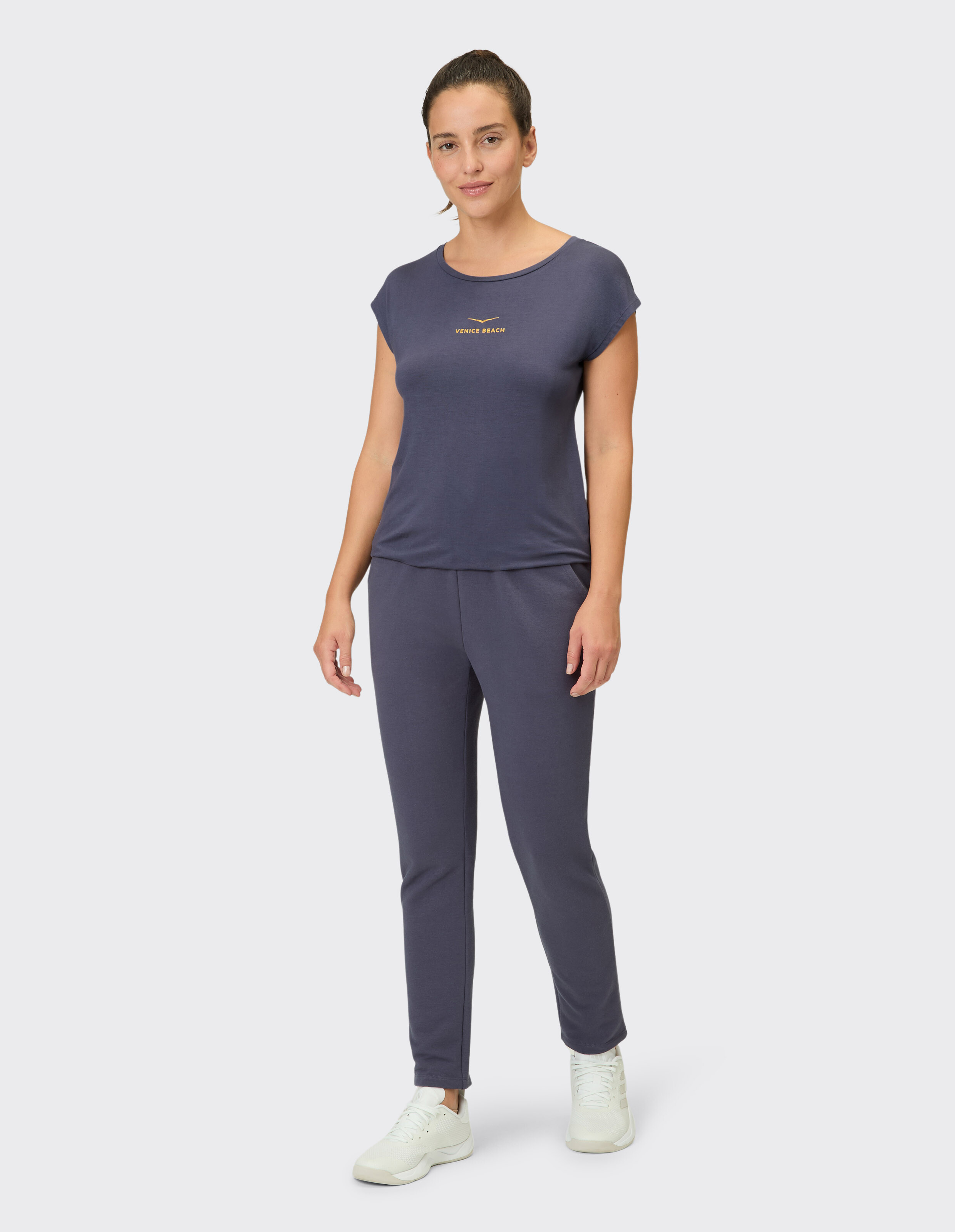 Frau trägt ein gemütliches dunkelblaues Lounge-Set mit einem Venice Beach-T-Shirt und passender Hose.