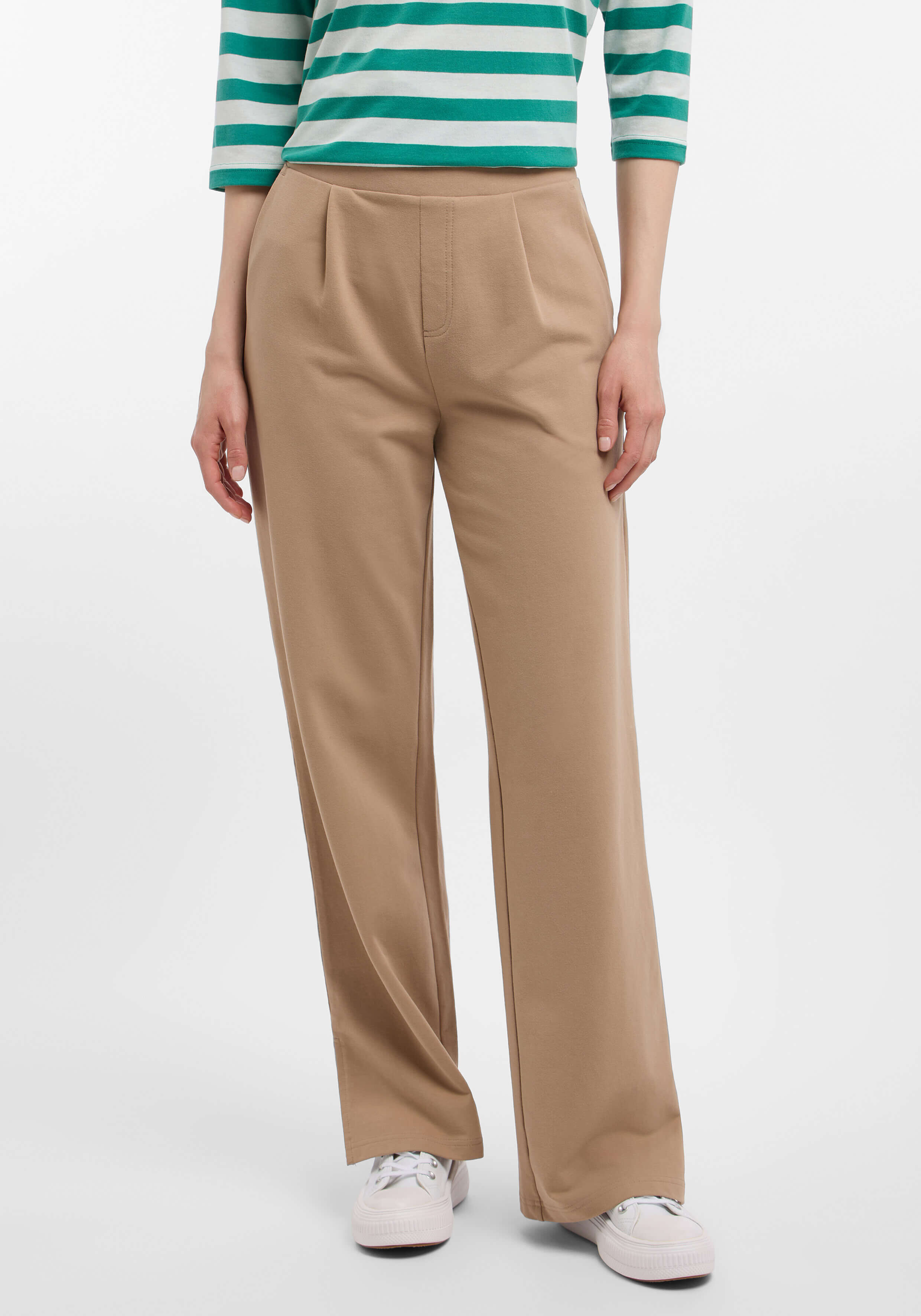 Frau trägt beige Hose mit weitem Bein und Bundfalten, gepaart mit einem grün-weiß gestreiften Oberteil.