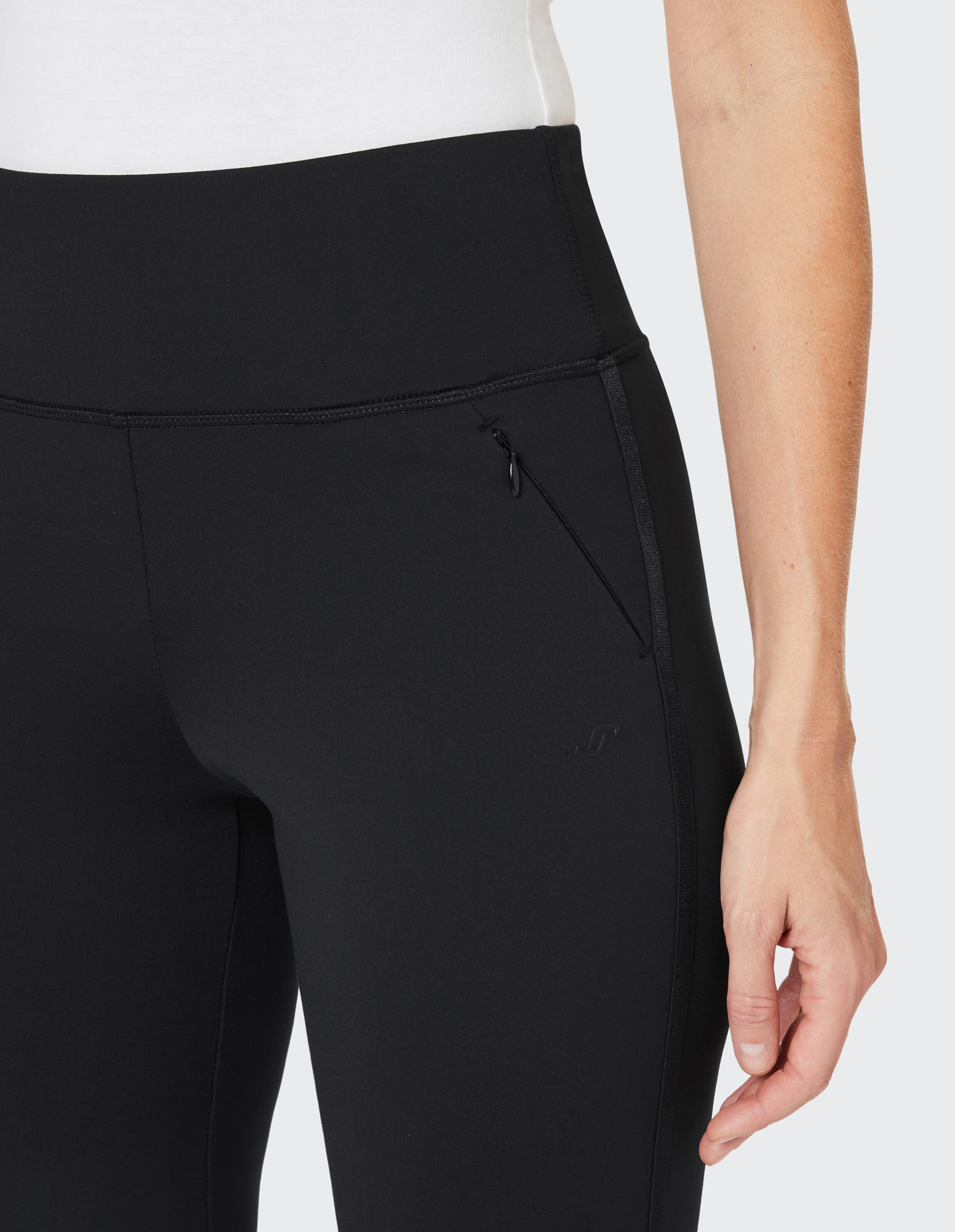 Schwarze Leggings mit breitem Bund, Ziernähten und Reißverschlusstasche, getragen von einer Person in weißem Oberteil.