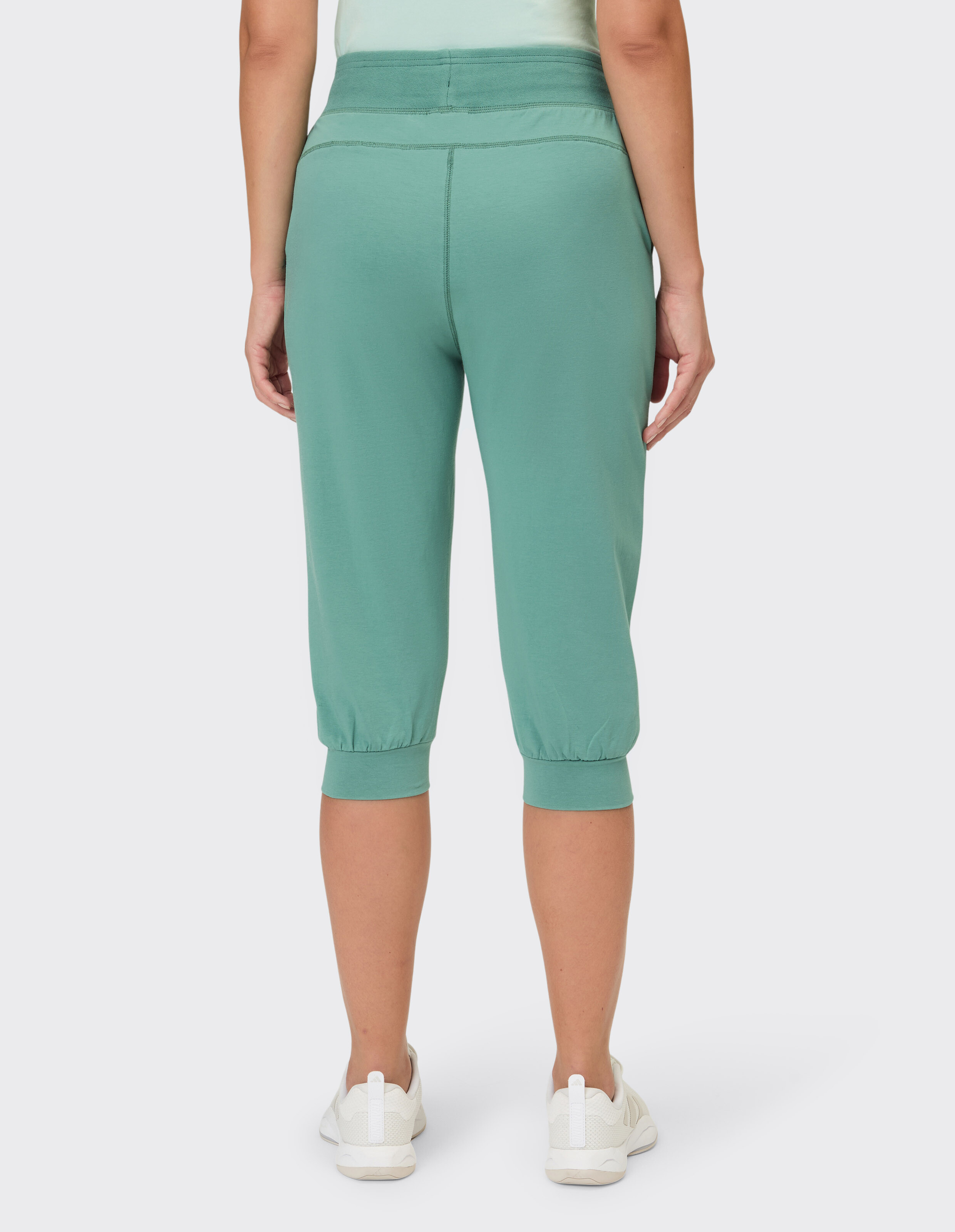 Rückansicht einer salbeigrünen, lässigen Capri-Loungehose mit elastischen Bündchen.
