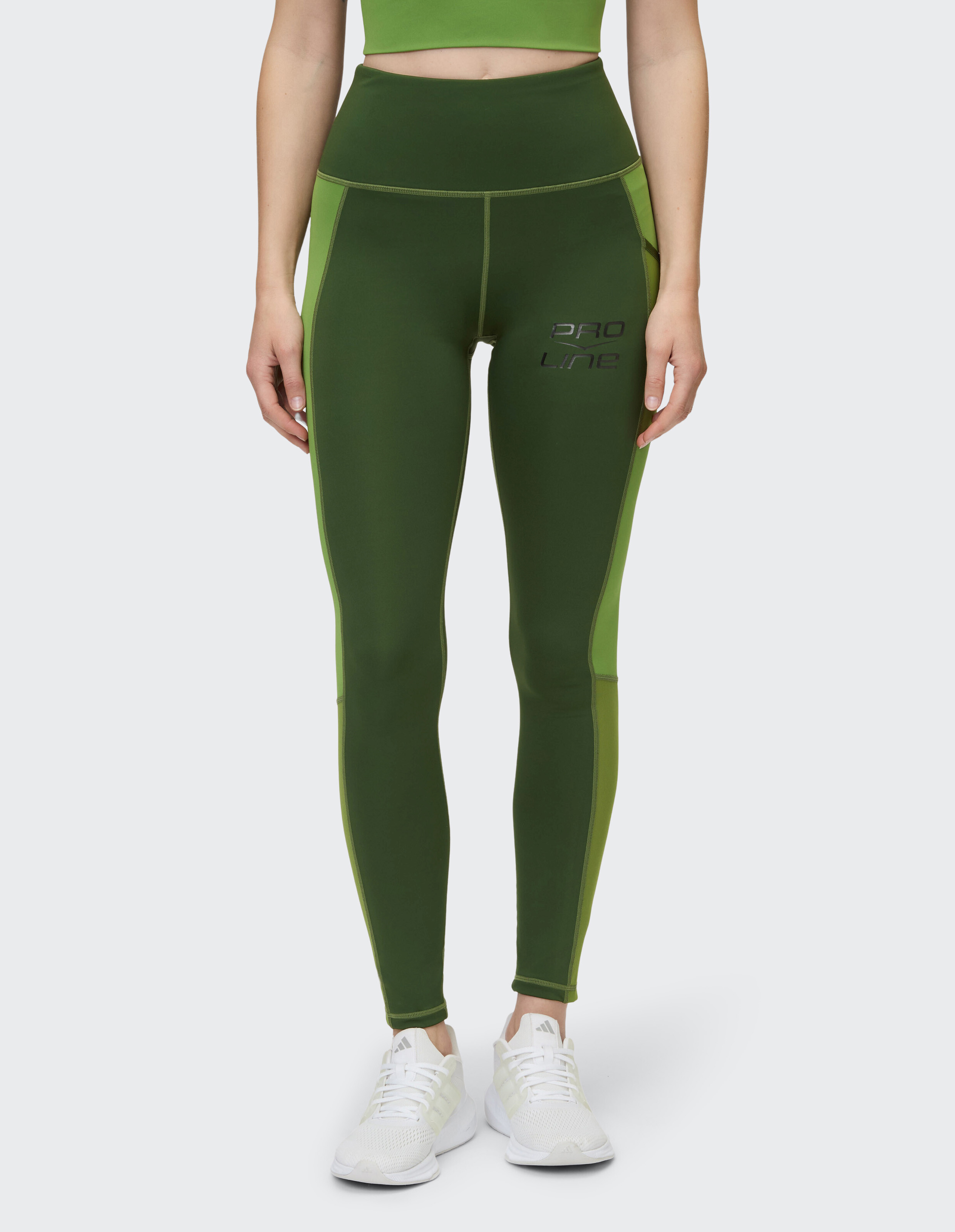 Das Model trägt grüne Leggings mit hohem Bund und passendem Crop-Top.