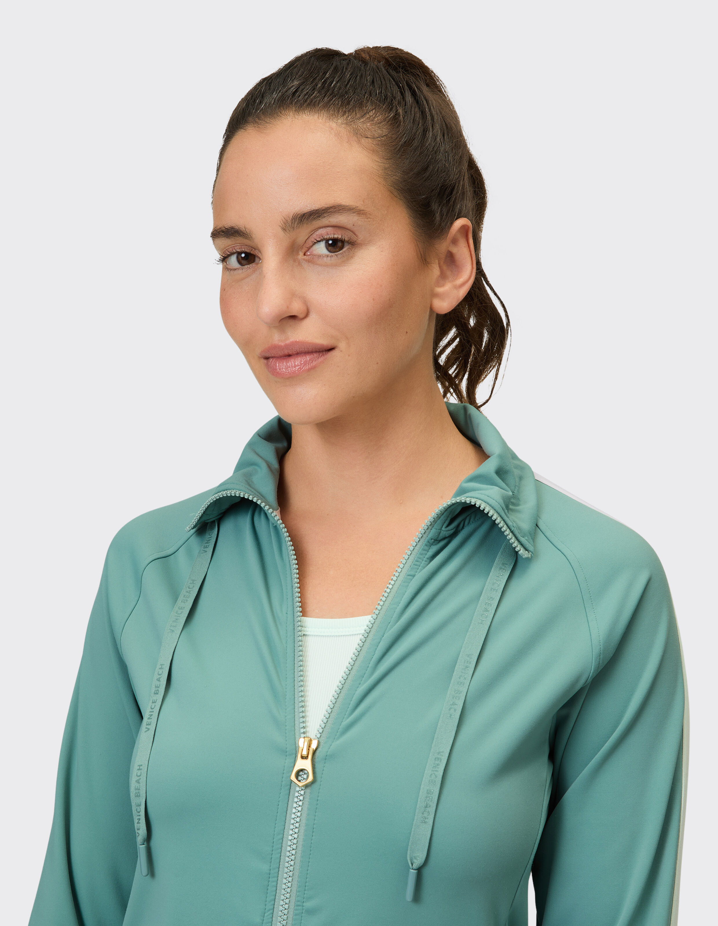 Nahaufnahme einer Frau in einer hellgrünen Jacke mit Reißverschluss, die einen lässigen Stil unterstreicht.