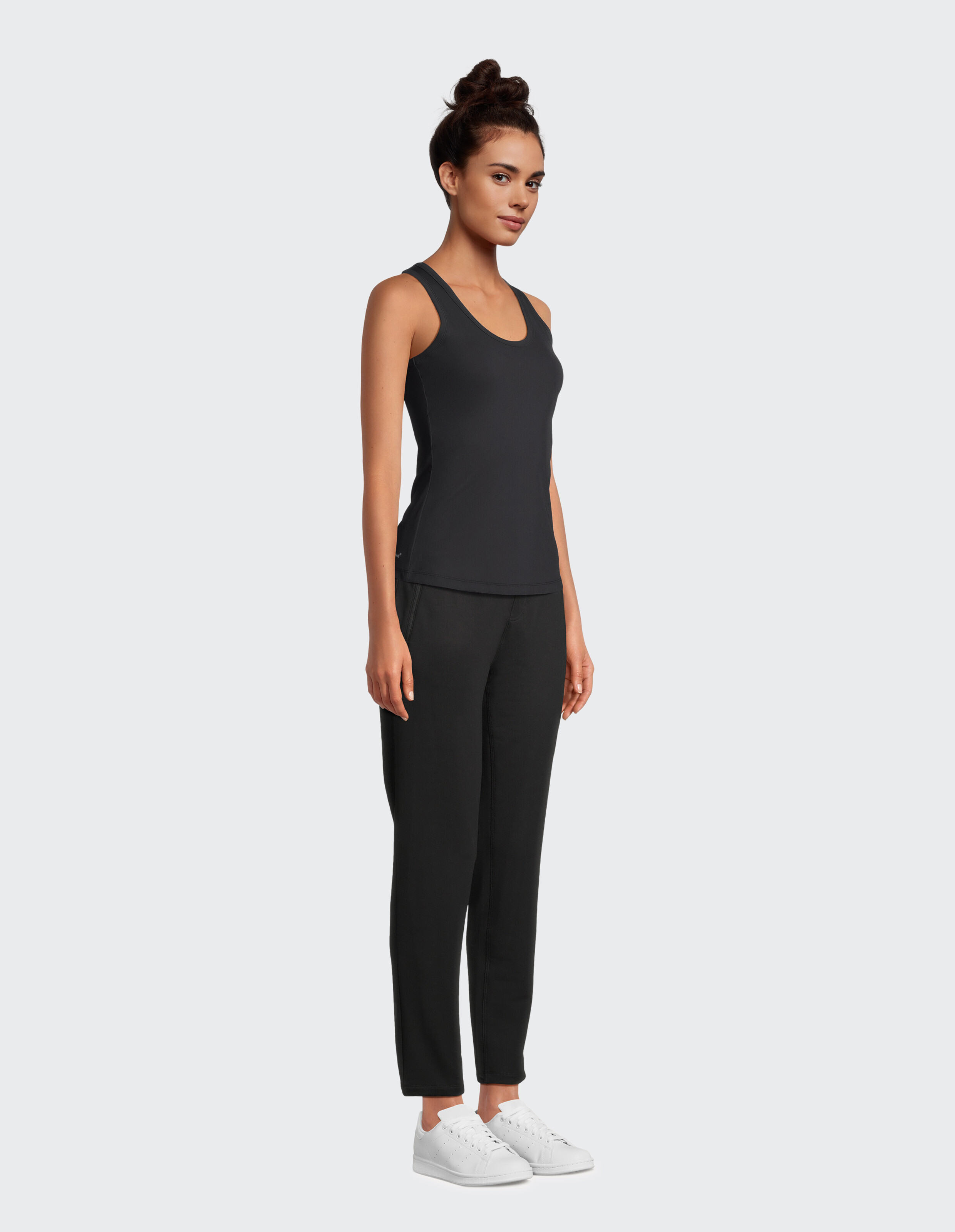 Frau in einem schwarzen Tanktop und einer Hose, gestylt für lässigen Komfort.