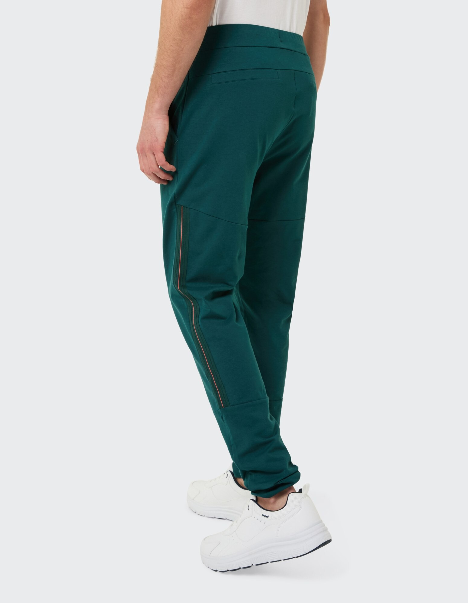 Blaugrüne Herren-Jogginghose mit seitlichen Reißverschlüssen, gepaart mit weißen Sneakers.