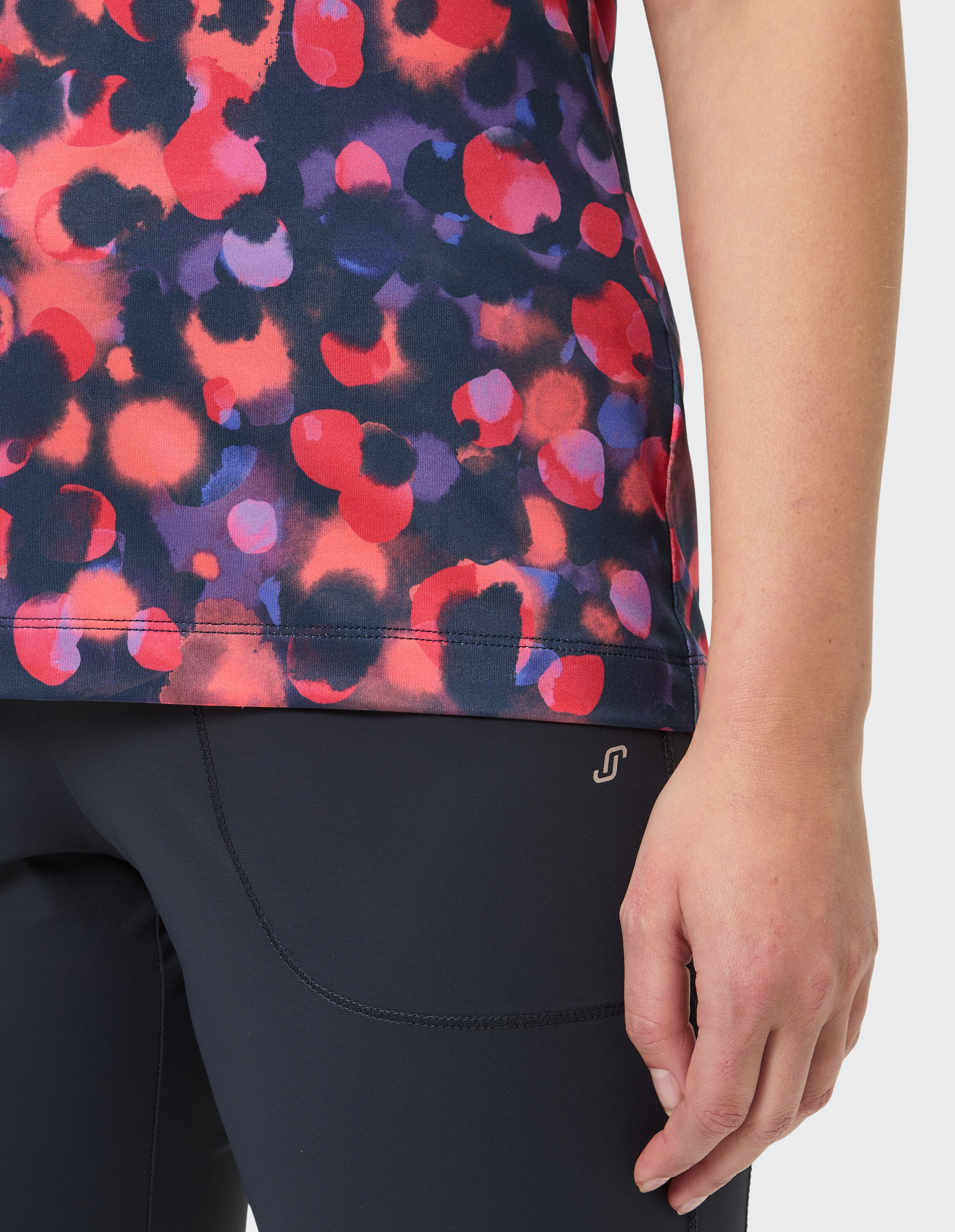 Nahaufnahme eines bunt gemusterten Oberteils gepaart mit dunklen Leggings, ideal für Freizeitkleidung.