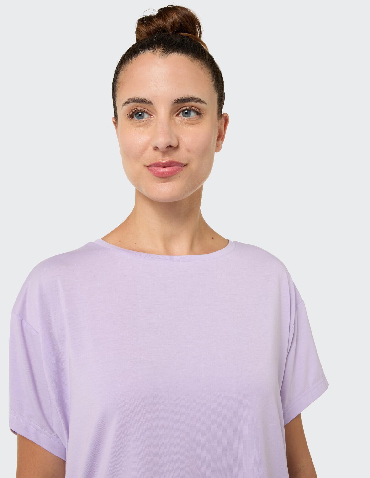 Nahaufnahme einer Frau in einem hellvioletten Freizeit-T-Shirt mit kurzen Ärmeln.