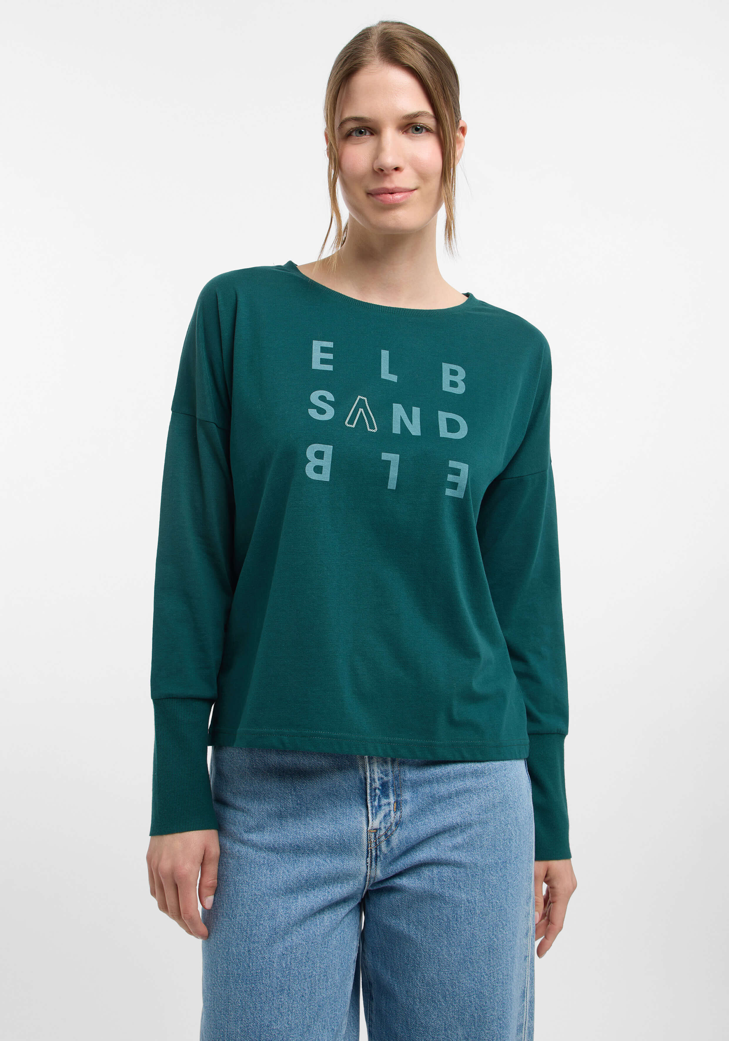 Frau trägt ein dunkelgrünes ELBSAND-Langarmshirt mit Logo-Print.