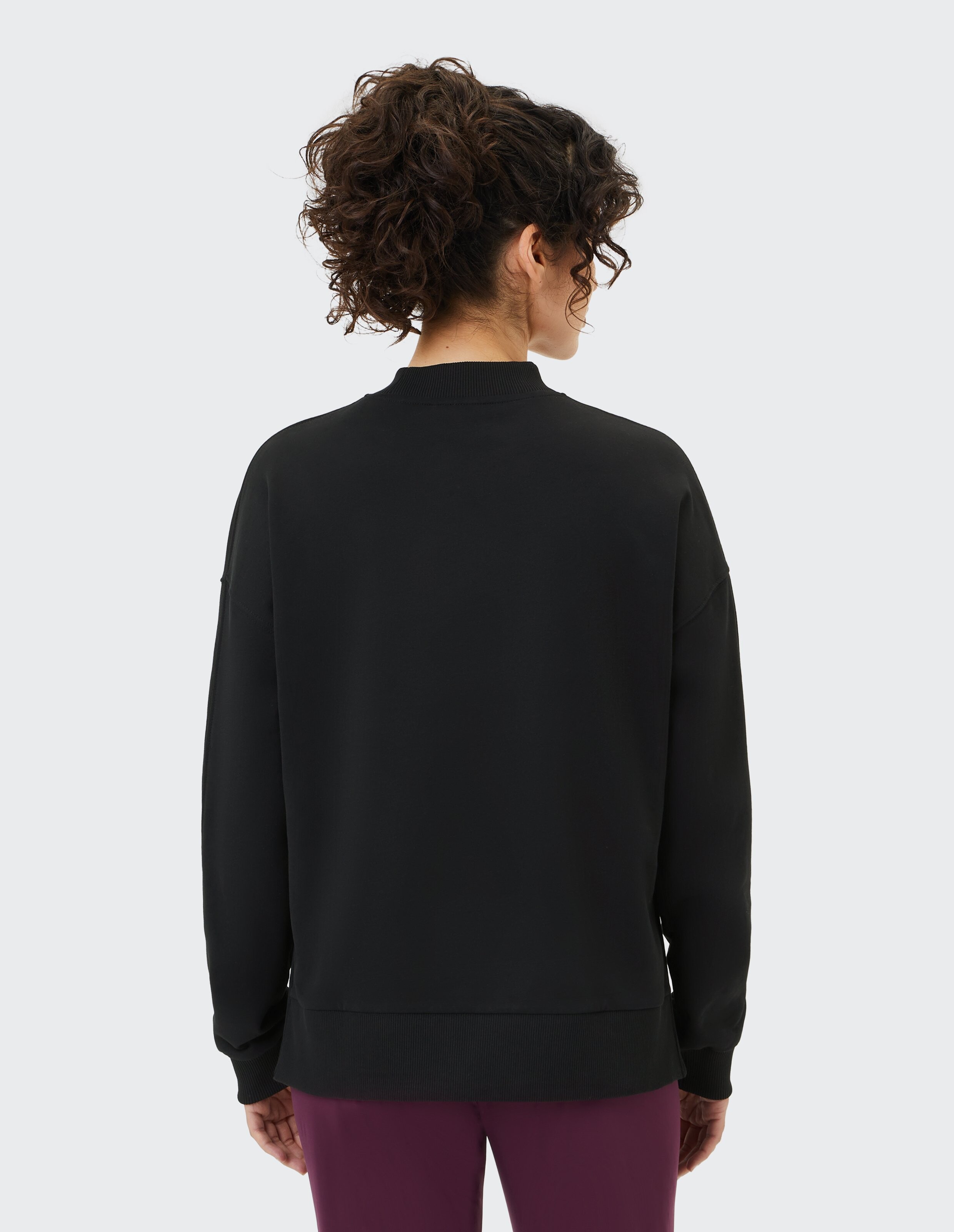 Rückansicht einer Frau in einem schwarzen, kuscheligen Sweatshirt, perfekt für Freizeitkleidung.