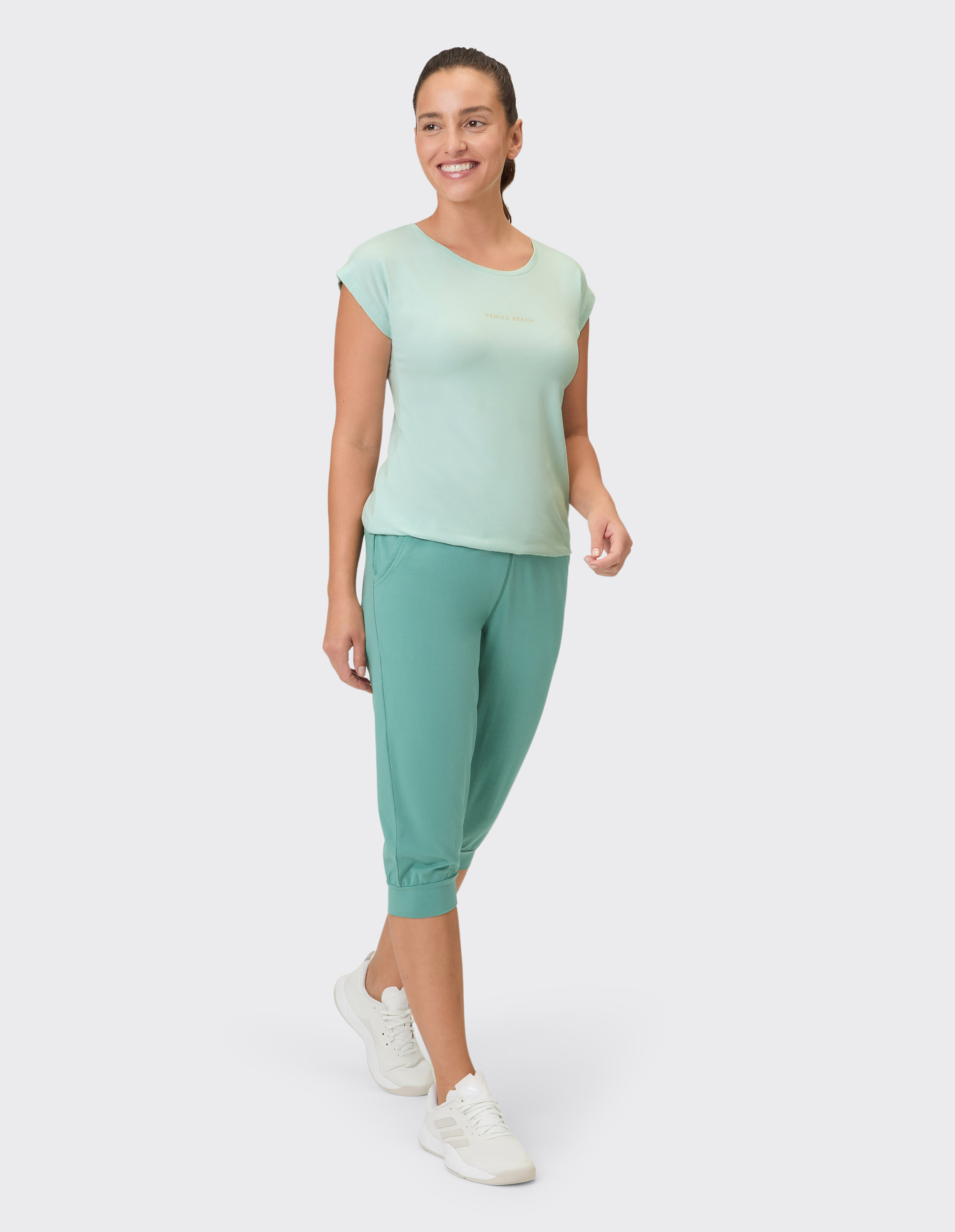 Frau trägt ein hellgrünes T-Shirt und eine passende Capri-Loungehose für lässigen Komfort.