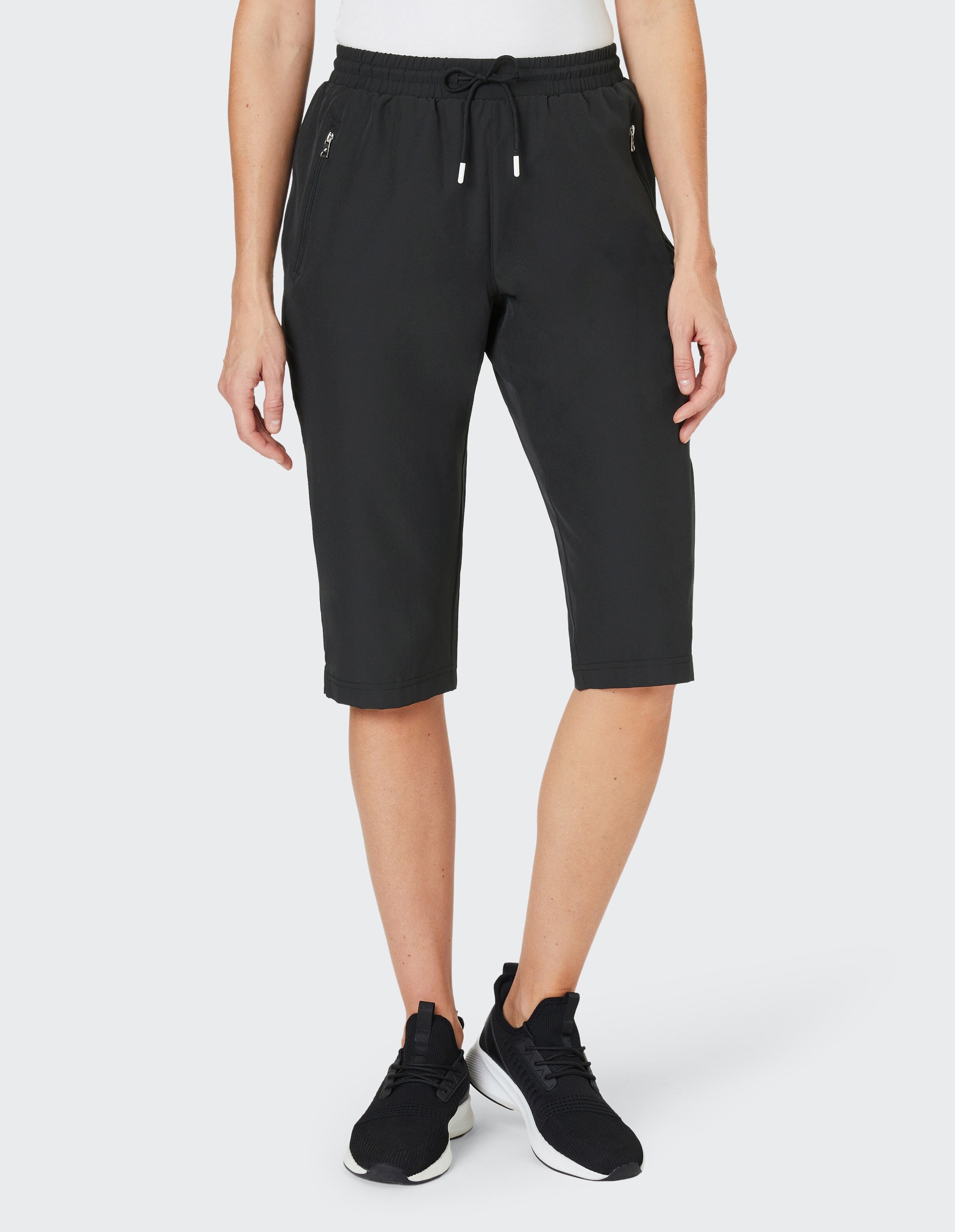 Schwarze, knielange Sporthose mit elastischem Bund, Kordelzug und seitlichen Reißverschlusstaschen vor weißem Hintergrund.