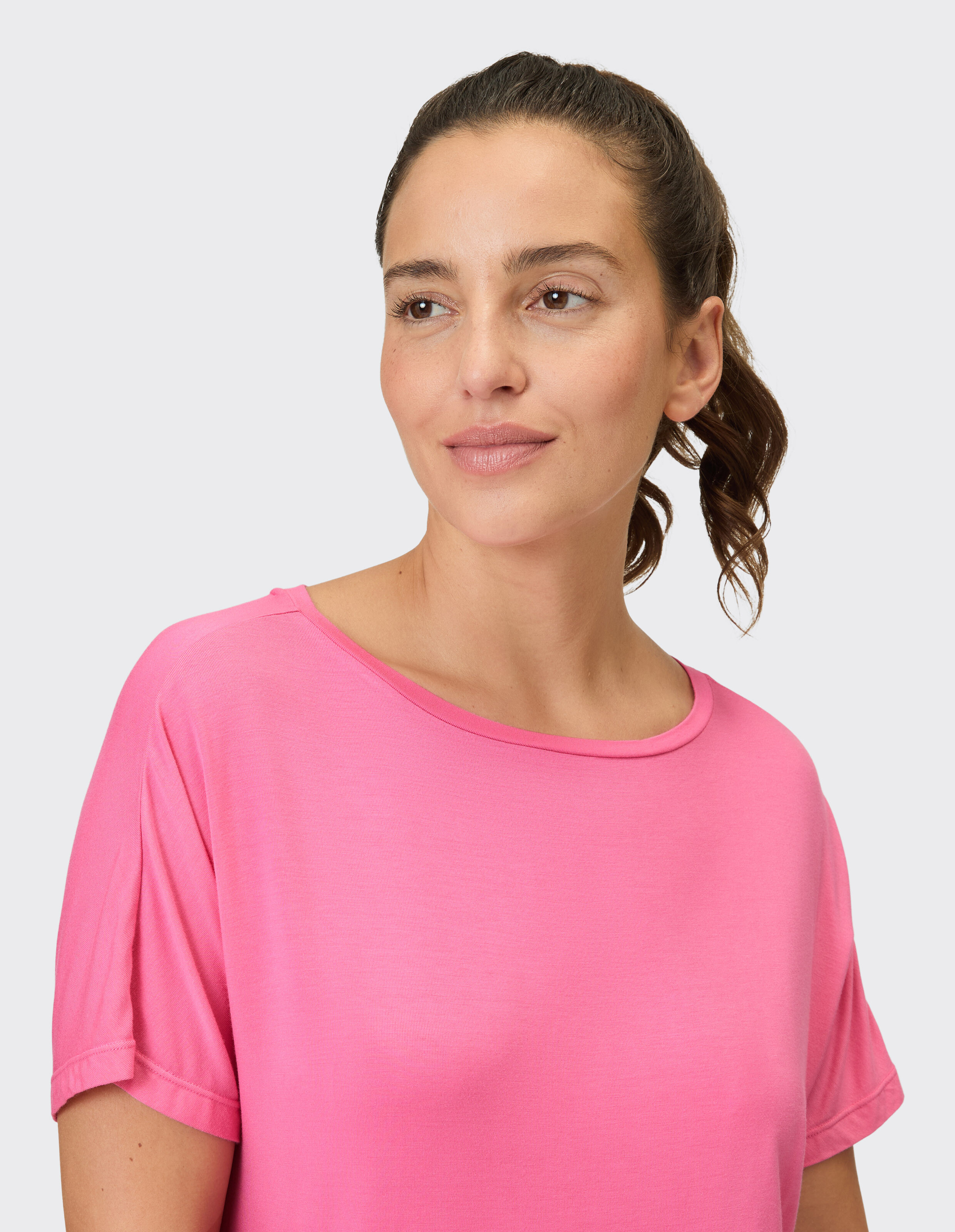 Nahaufnahme einer Frau, die ein zartrosa Freizeit-T-Shirt mit kurzen Ärmeln trägt.