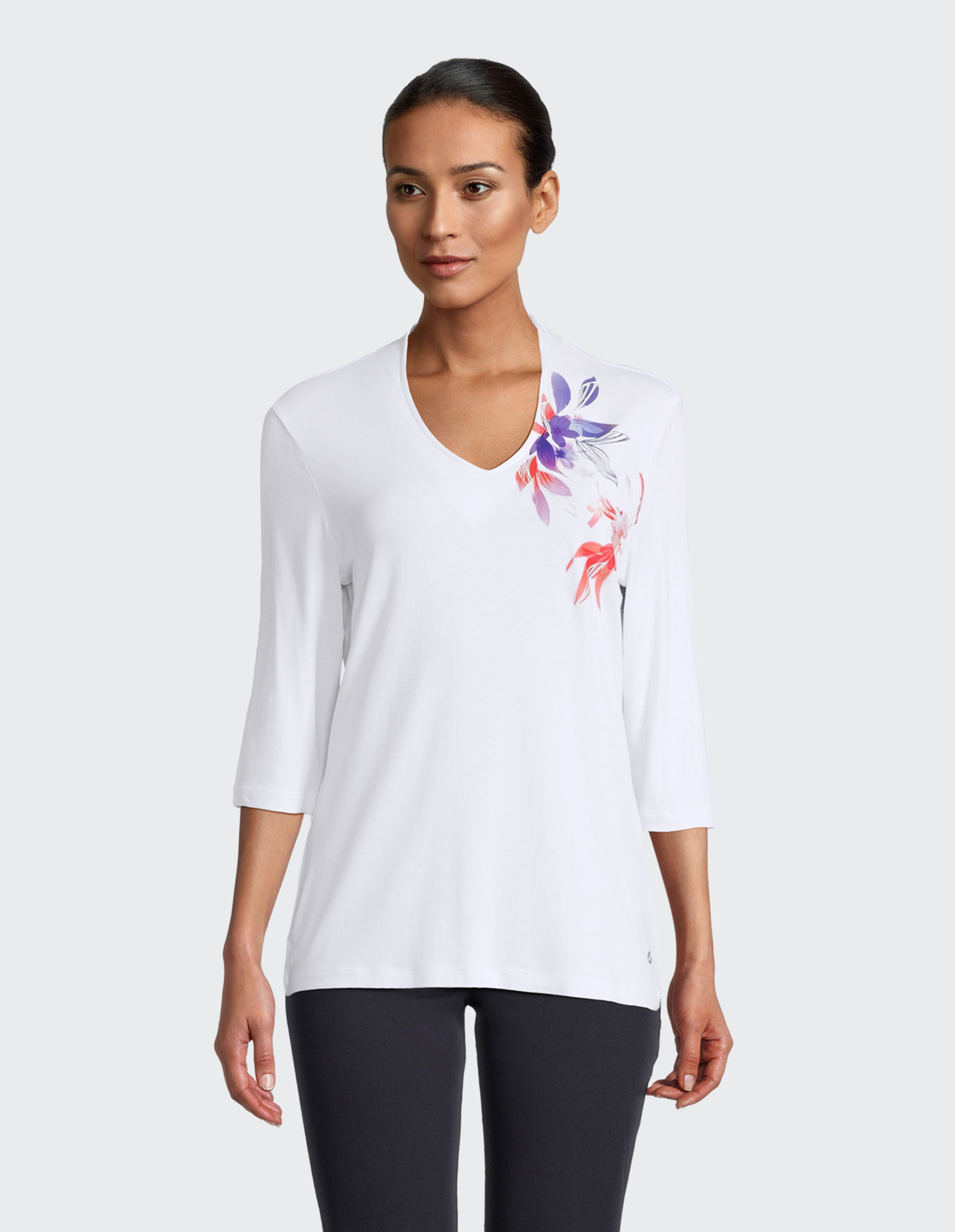 Eine weiße Damenbluse mit V-Ausschnitt und einem bunten Blumenprint.