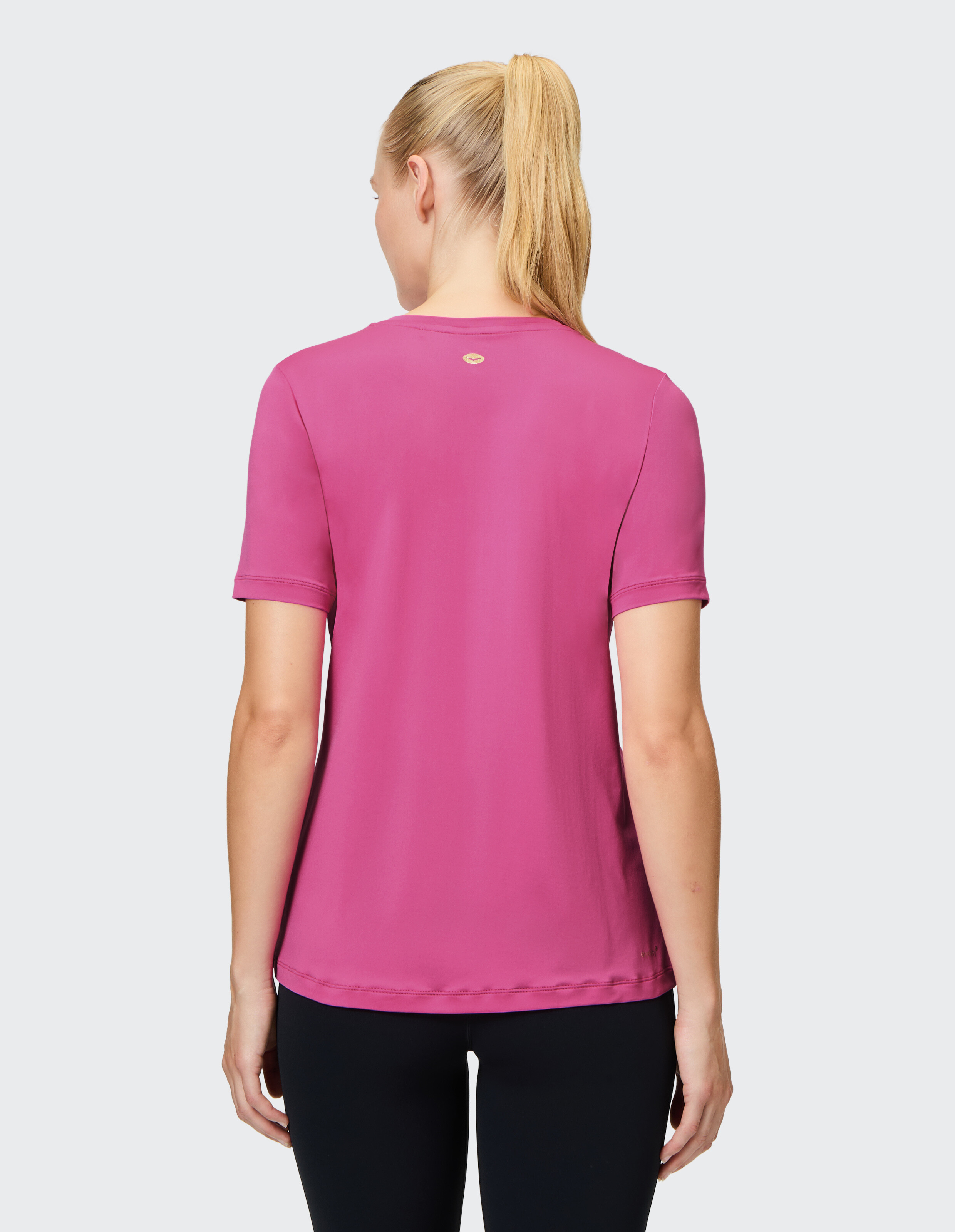 Rückansicht einer Frau, die zum Entspannen ein rosa kurzärmliges Freizeit-T-Shirt trägt.