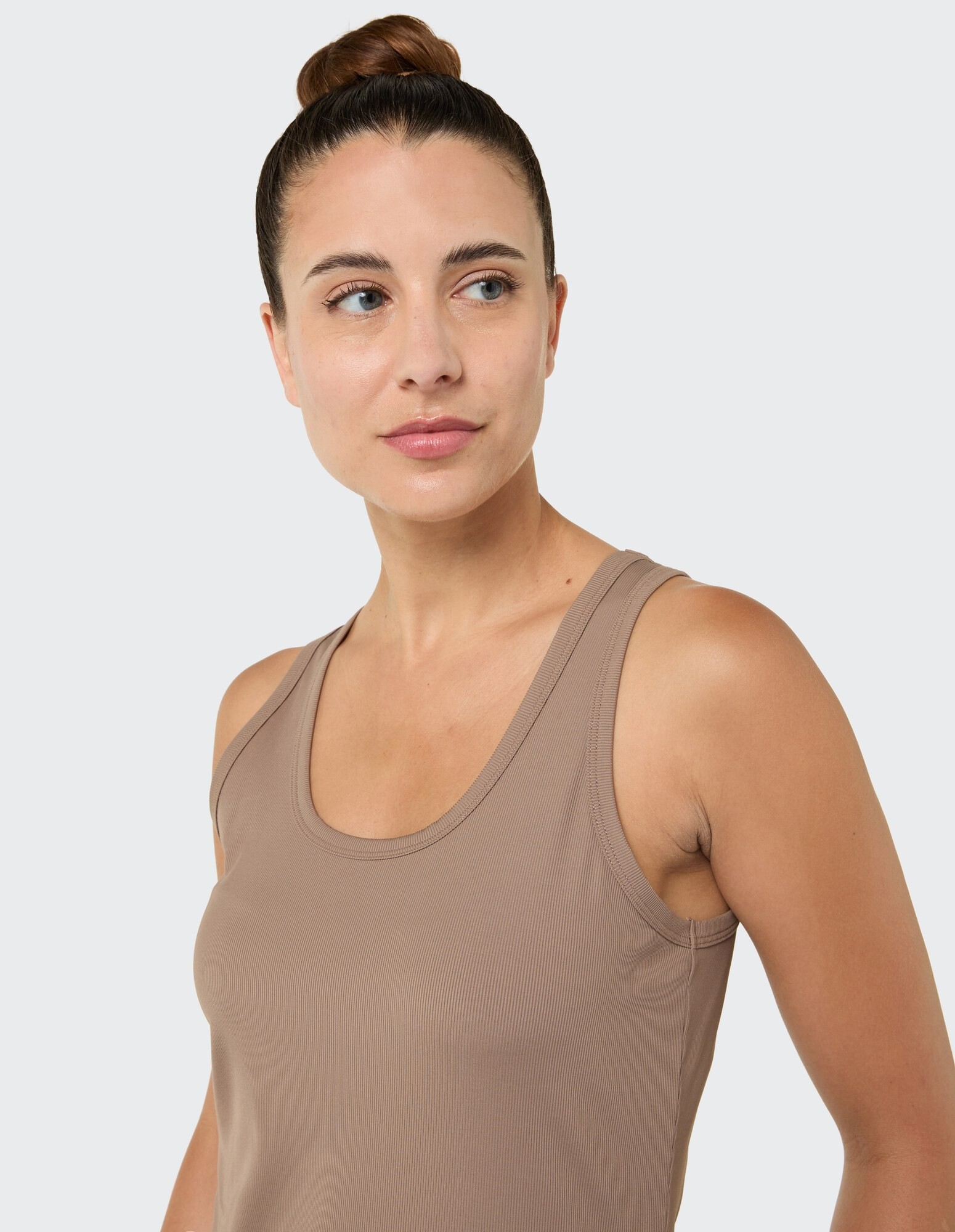 Das Model trägt ein braunes, geripptes Tanktop und zeigt einen lässigen und bequemen Stil.