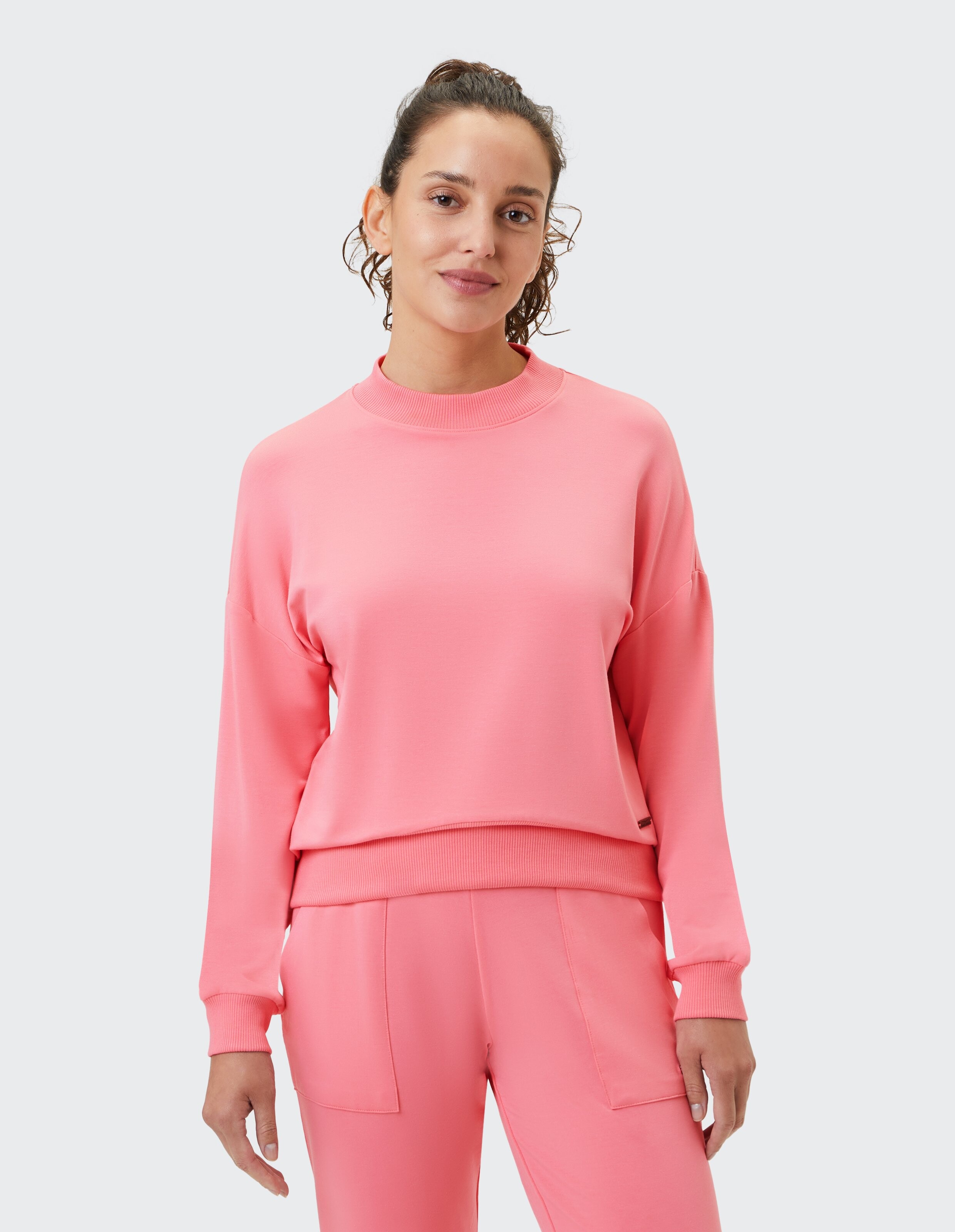 Frau trägt ein gemütliches rosafarbenes ELBSAND-Freizeit-Sweatshirt zum Faulenzen.