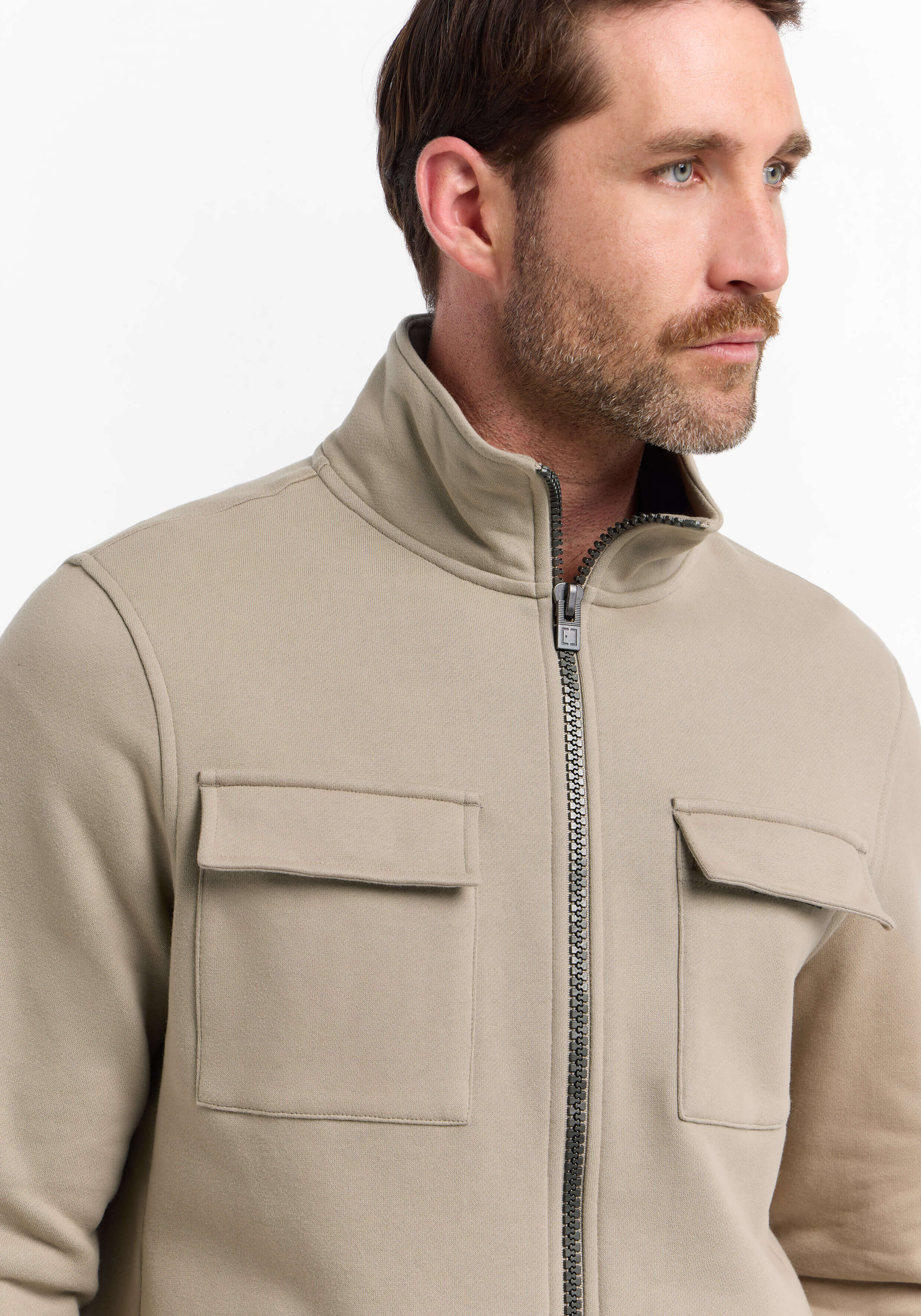 Mann trägt eine gemütliche beige Jacke mit Reißverschluss und Brusttaschen für lässigen Stil.