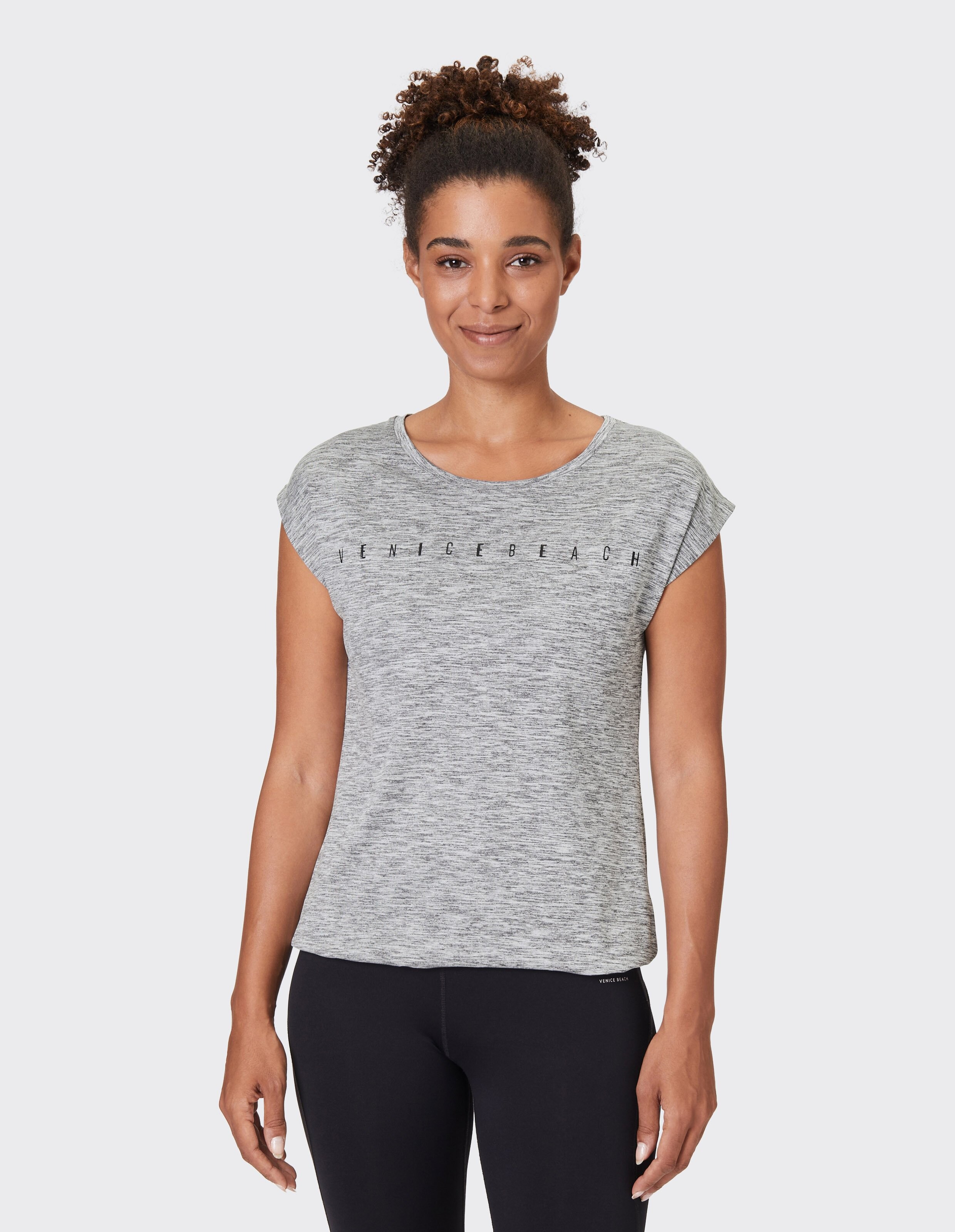 Frau trägt ein grau meliertes Venice Beach-Freizeit-T-Shirt zum Faulenzen.
