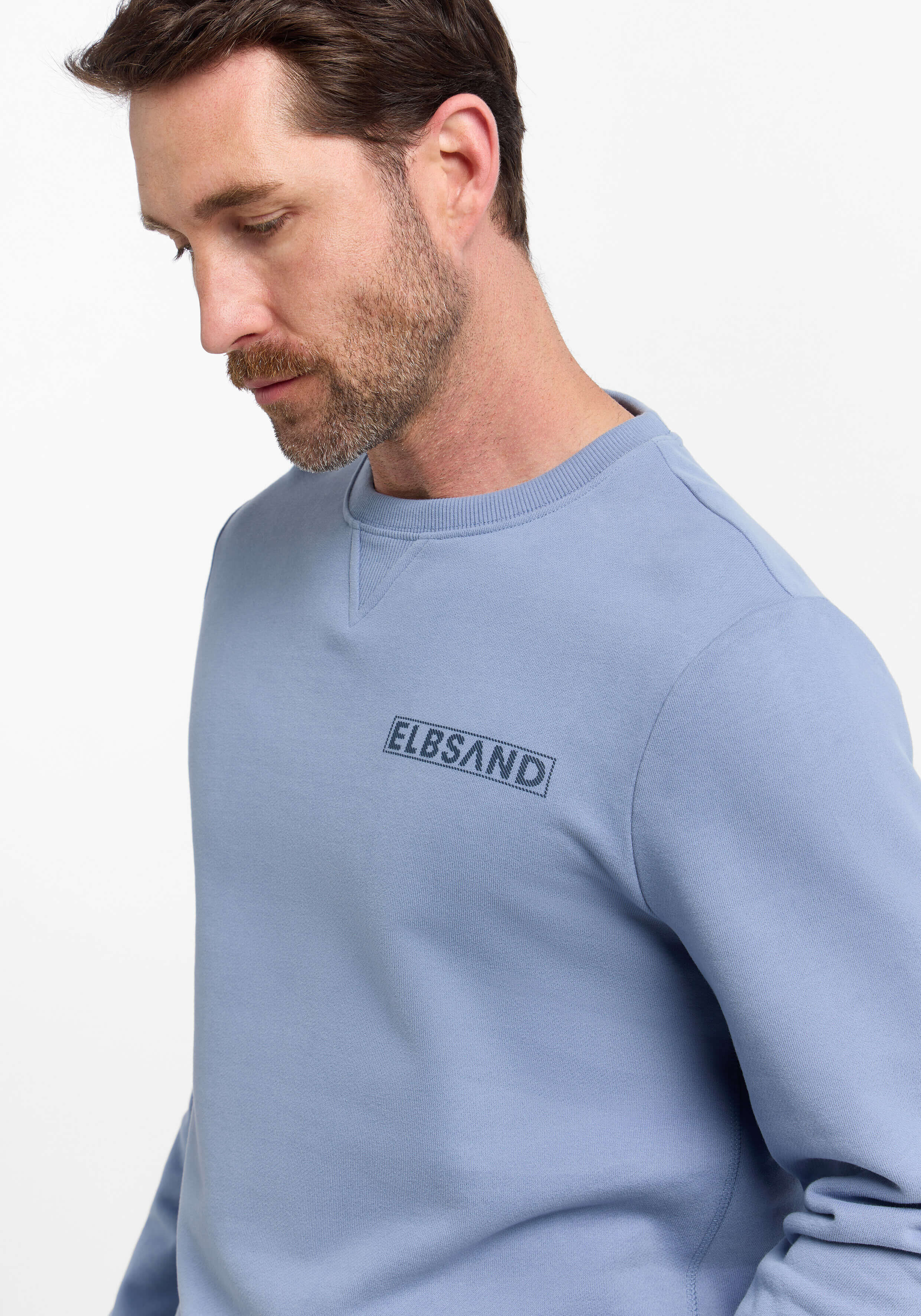Mann trägt ein gemütliches blaues ELBSAND-Sweatshirt mit Rundhalsausschnitt für einen lässigen Alltagsstil.