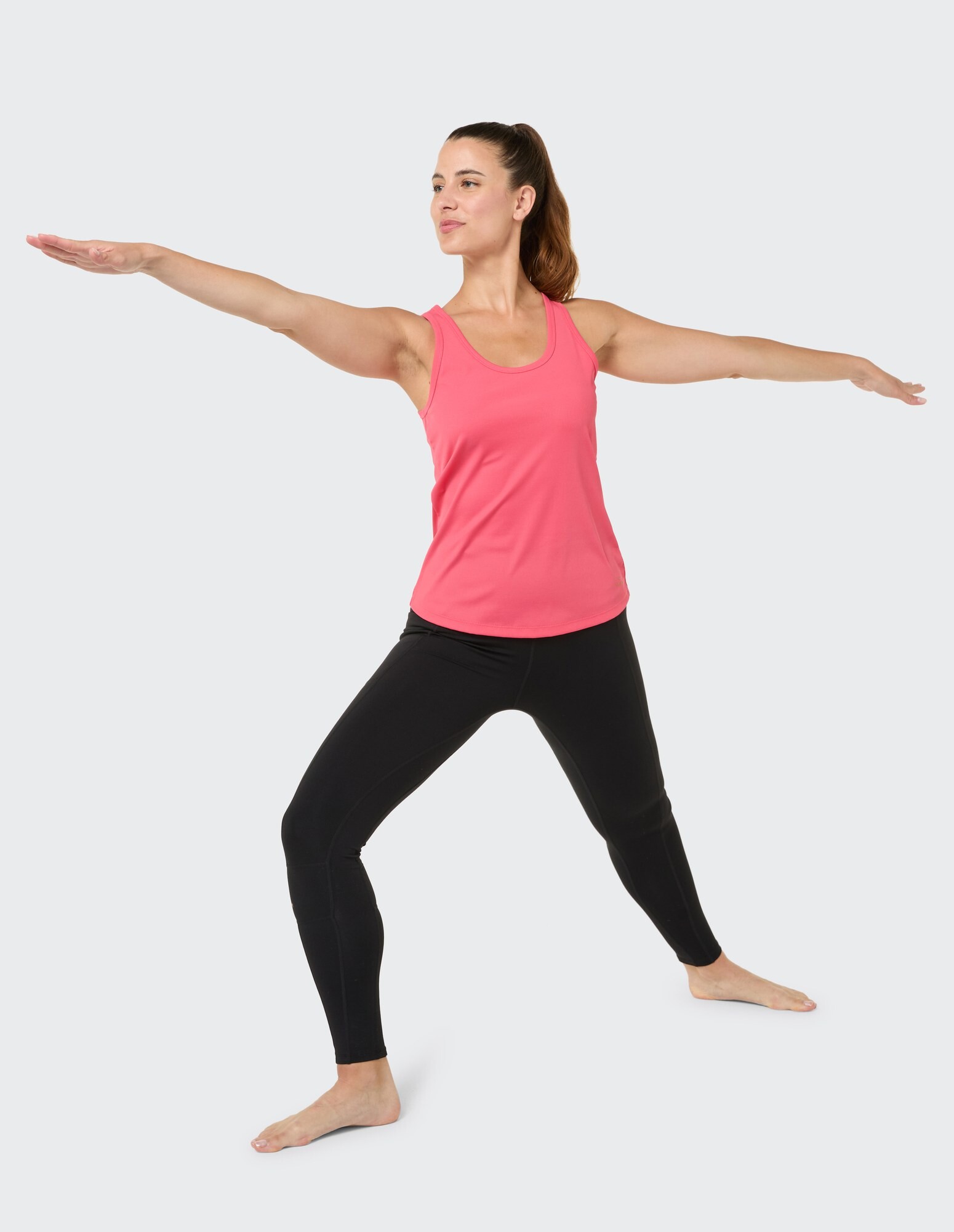 Frau in rosa Tanktop und schwarzen Leggings macht eine Yoga-Pose.