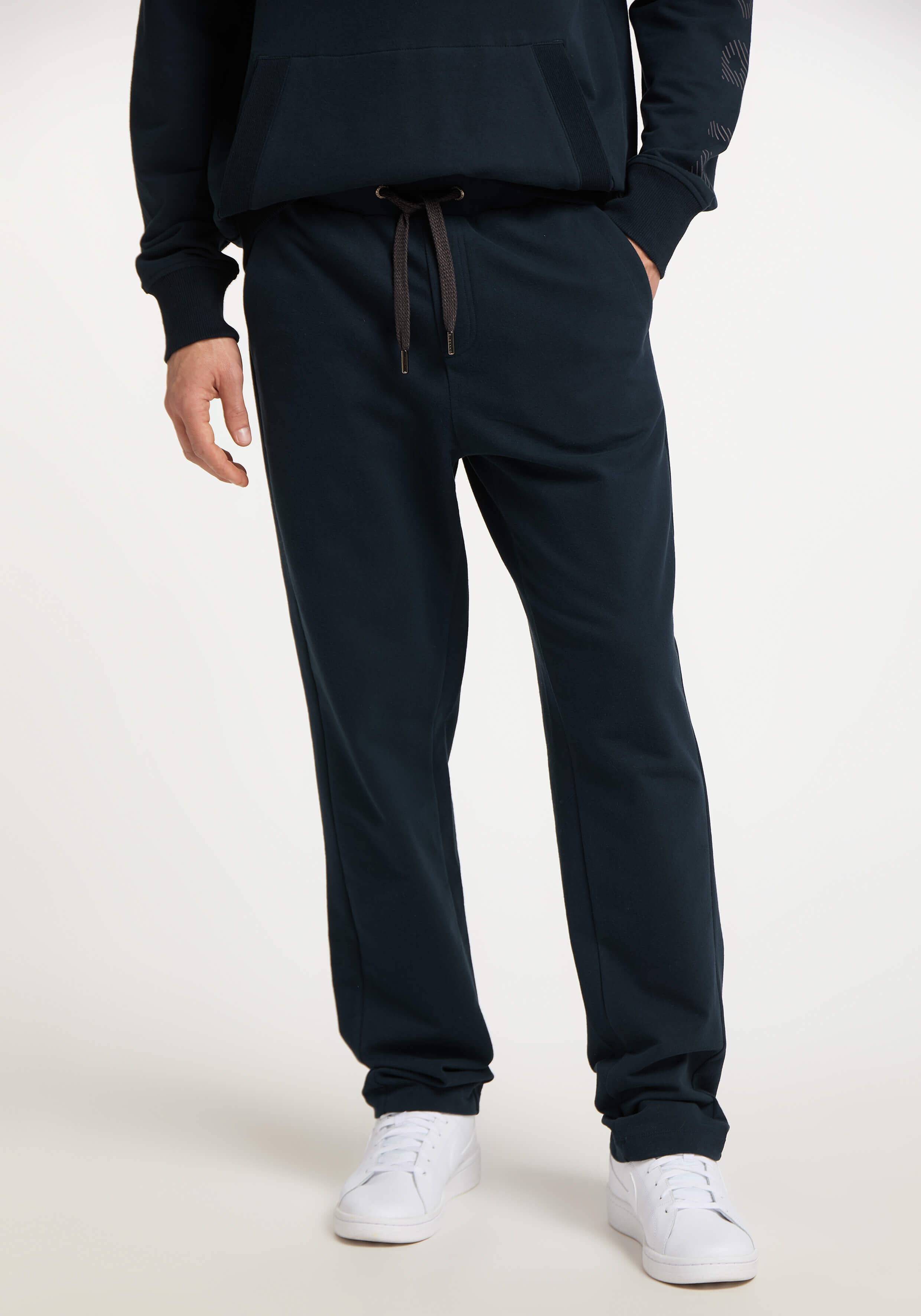 Mann trägt gemütliche dunkelblaue Freizeit-Jogginghose mit Kordelzug in der Taille.