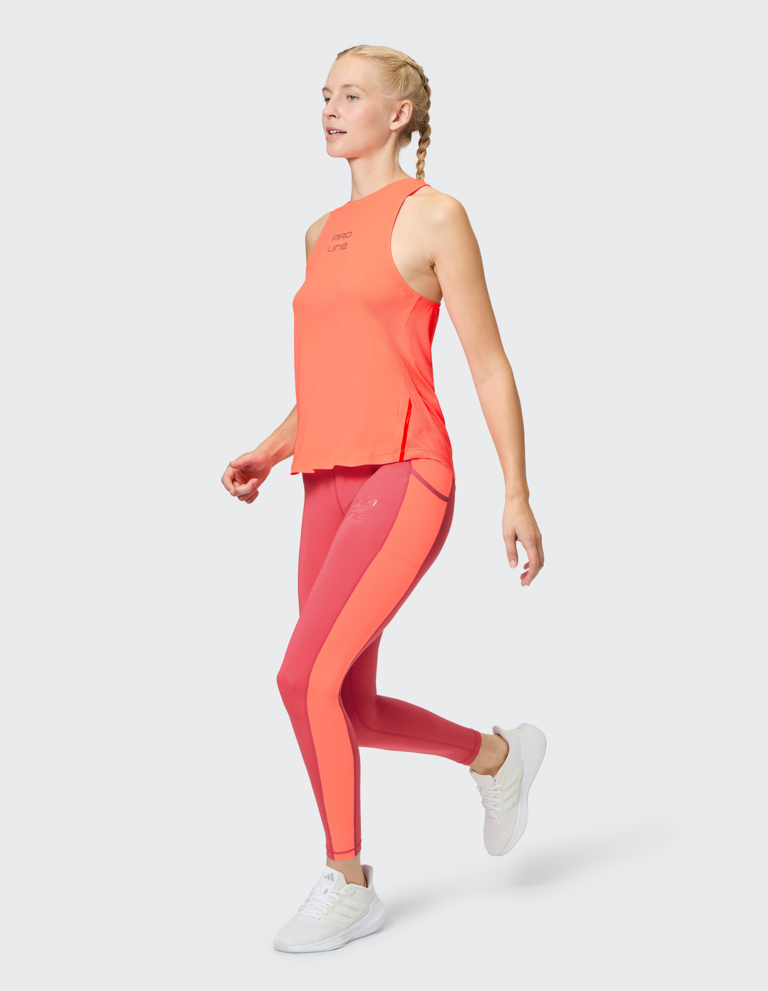 Frau in leuchtend orangefarbenem Tanktop und rosa Leggings, ideal für lässige Workouts.