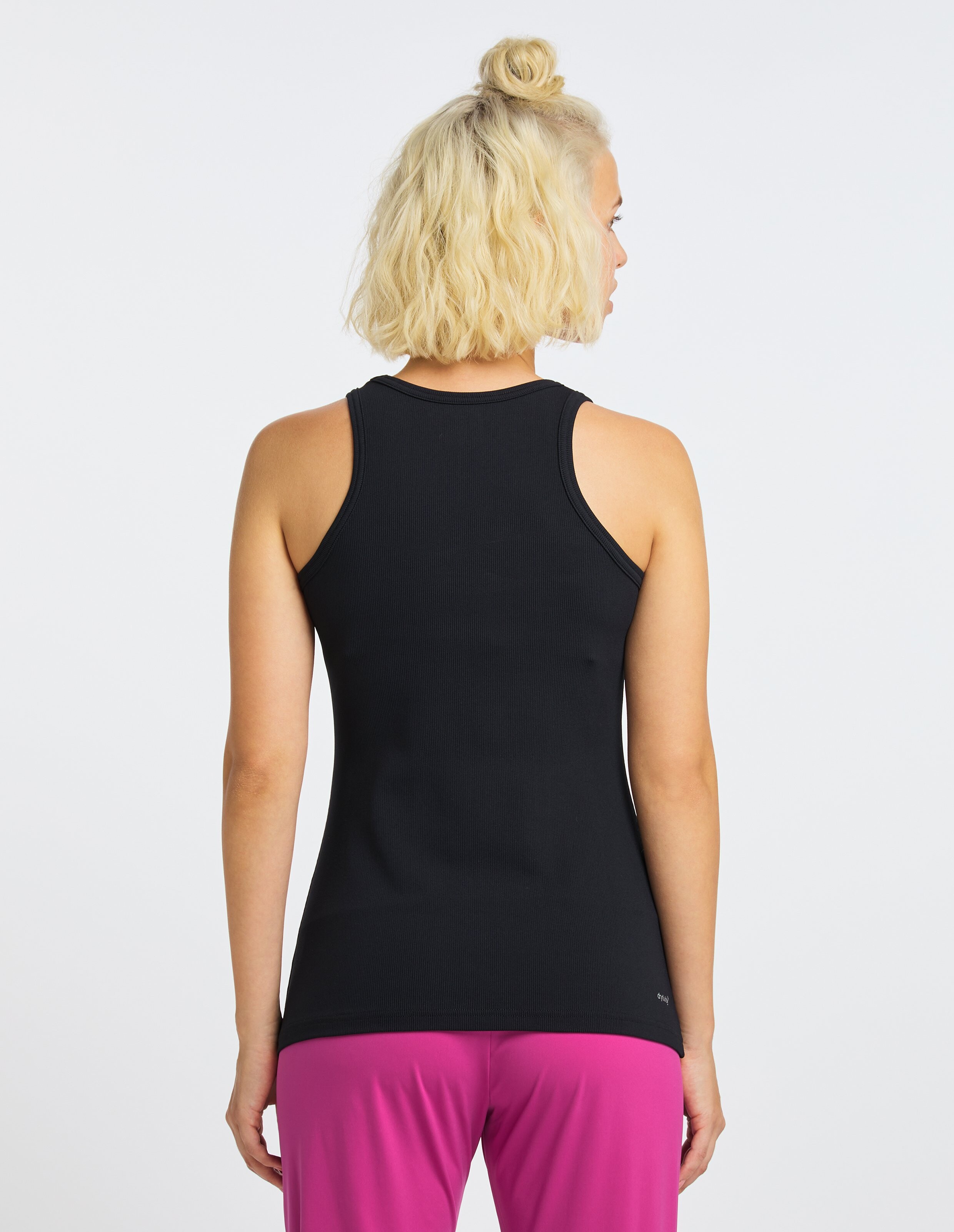 Rückansicht einer Frau in einem schwarzen Tanktop und einer rosa Hose, die einen lässigen Stil zur Schau stellt.