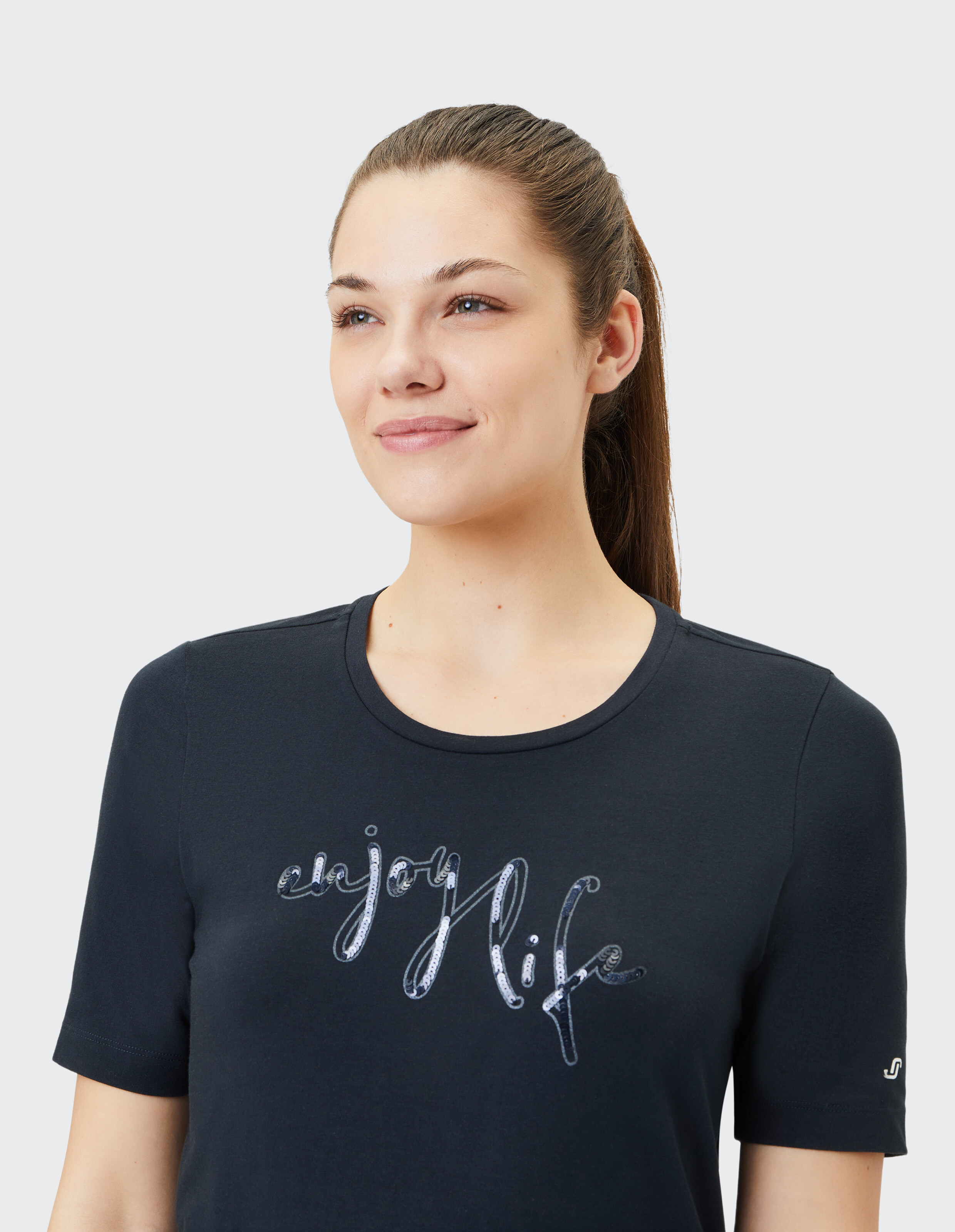 Das Model trägt ein dunkelblaues T-Shirt mit der Aufschrift „Enjoy Life“, perfekt für Freizeitausflüge.