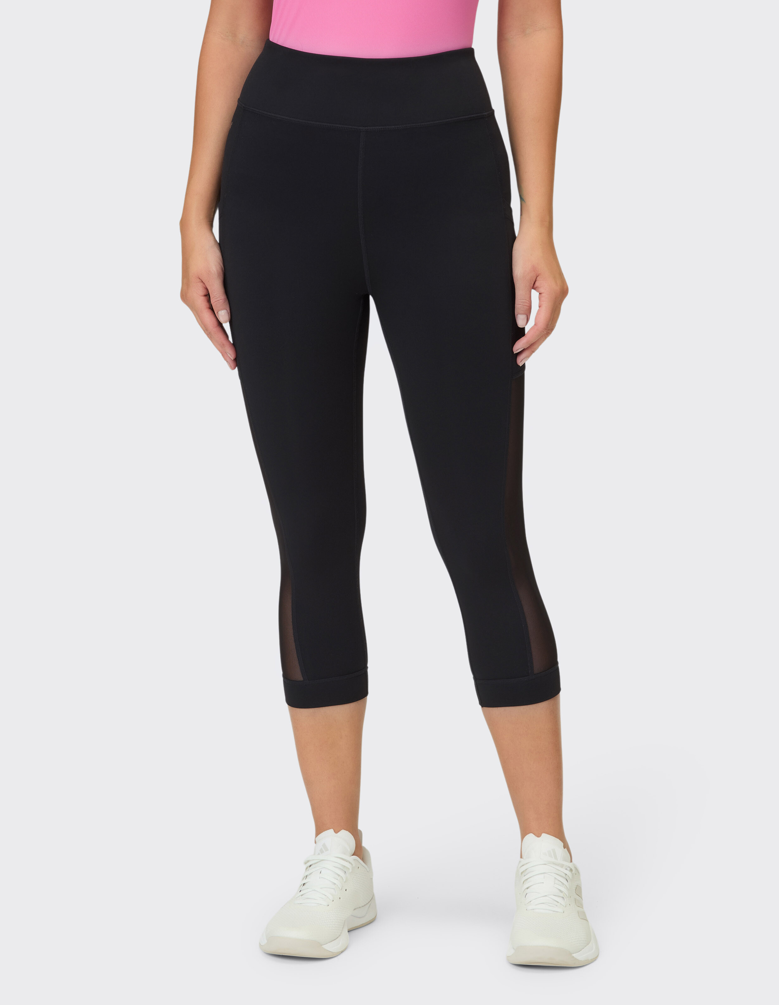 Frau trägt schwarze Capri-Leggings mit hoher Taille und Mesh-Seiteneinsätzen für Freizeitkleidung.