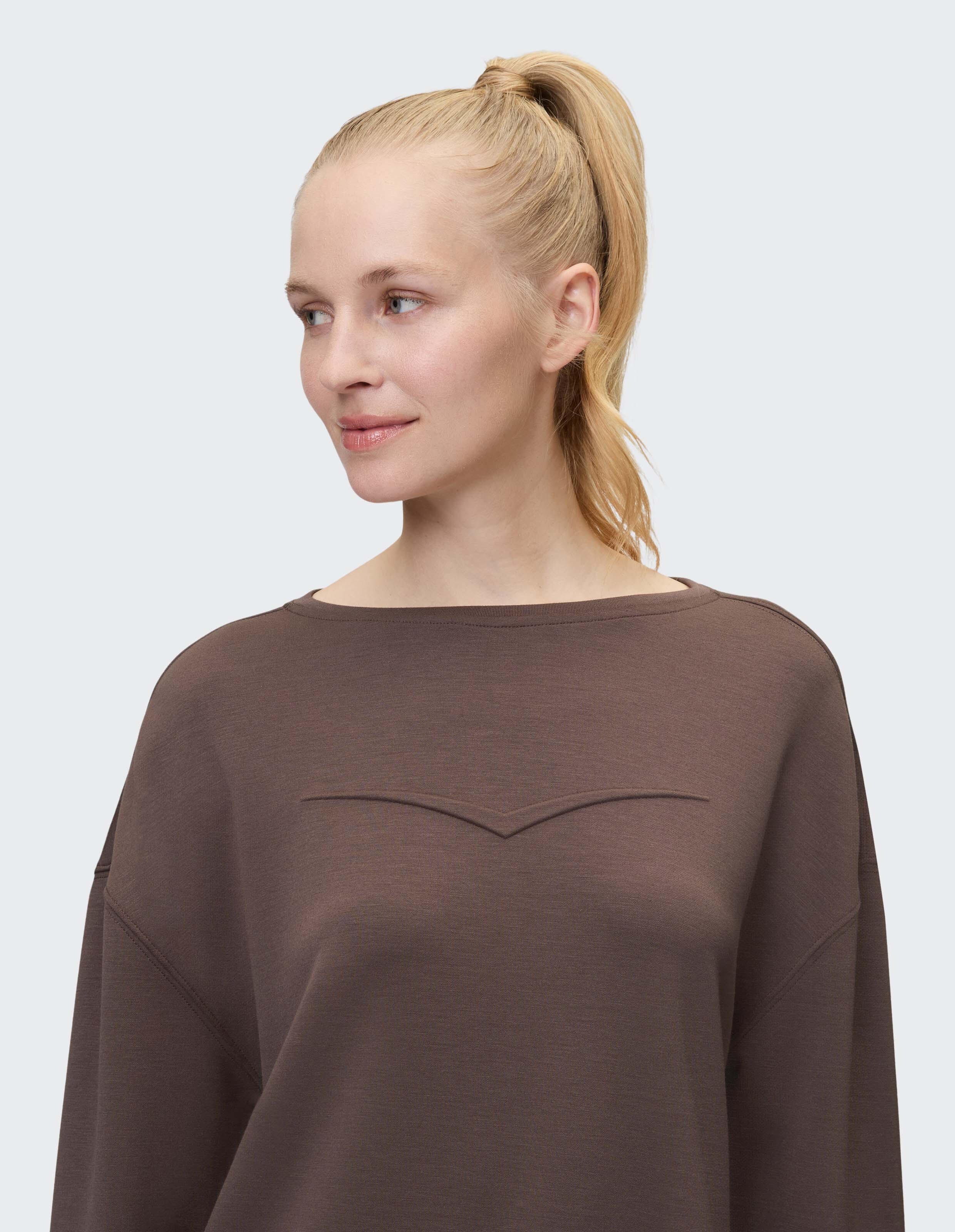 Frau trägt ein gemütliches braunes Venice Beach April-Sweatshirt zum lässigen Faulenzen.