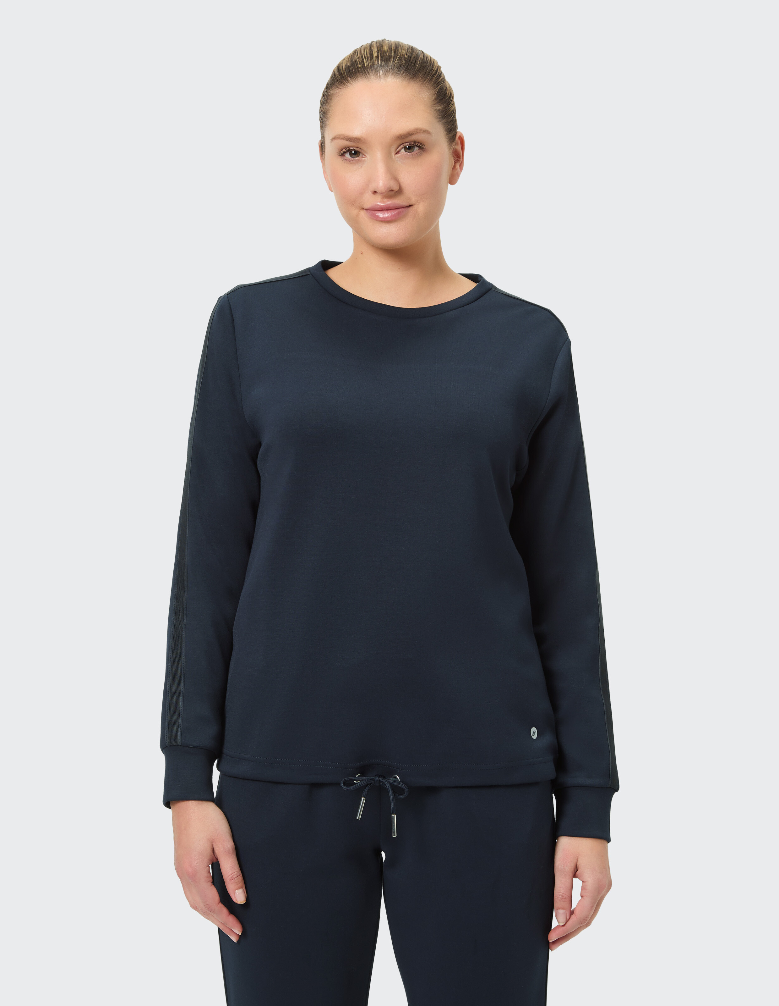 Das Model trägt ein dunkelblaues Langarm-Sweatshirt mit lockerer Passform und Kordelzug am Saum, ideal für Freizeitkleidung.