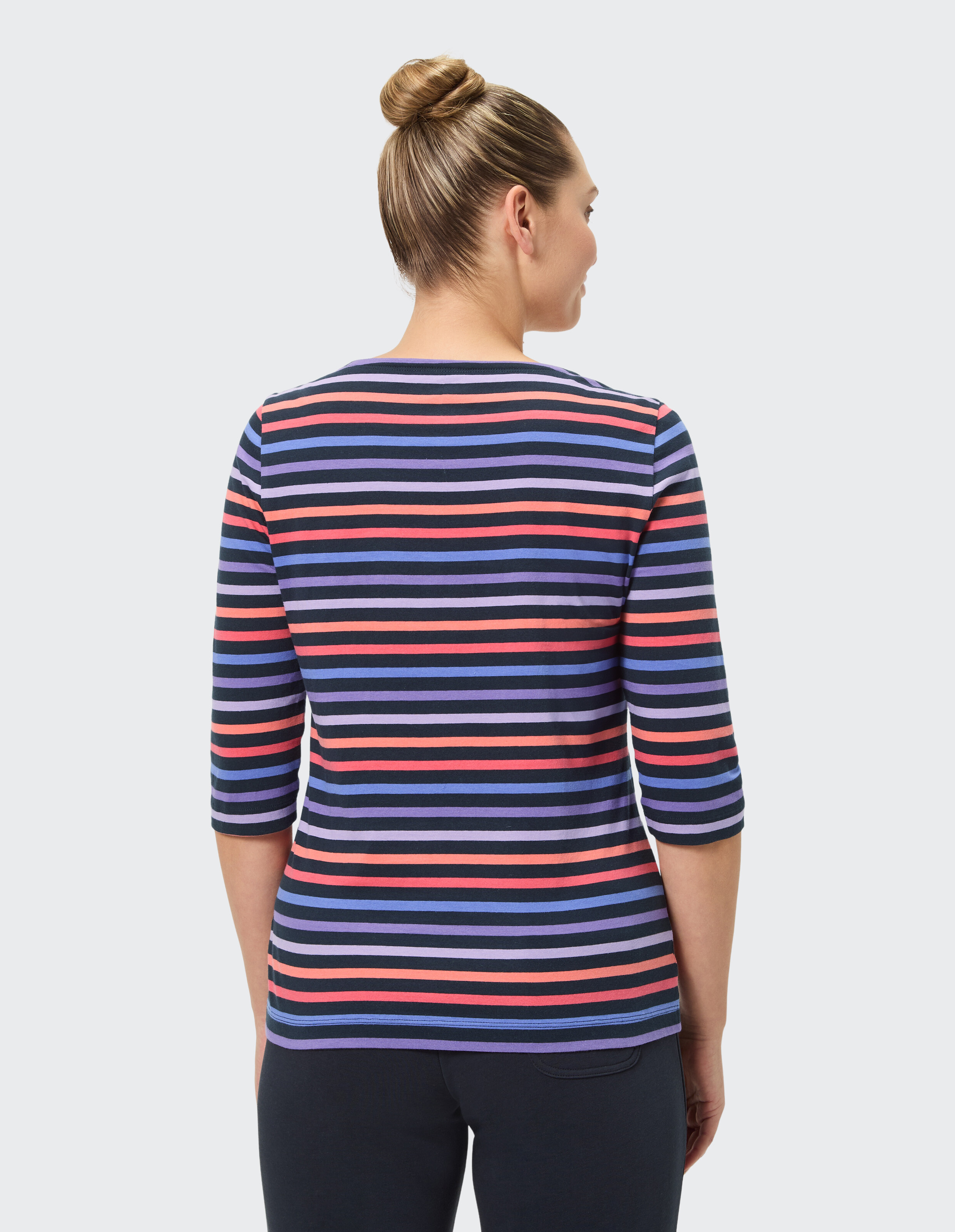 Rückansicht einer Frau in einem gestreiften Freizeitoberteil in den Farben Lila, Rot und Marineblau.