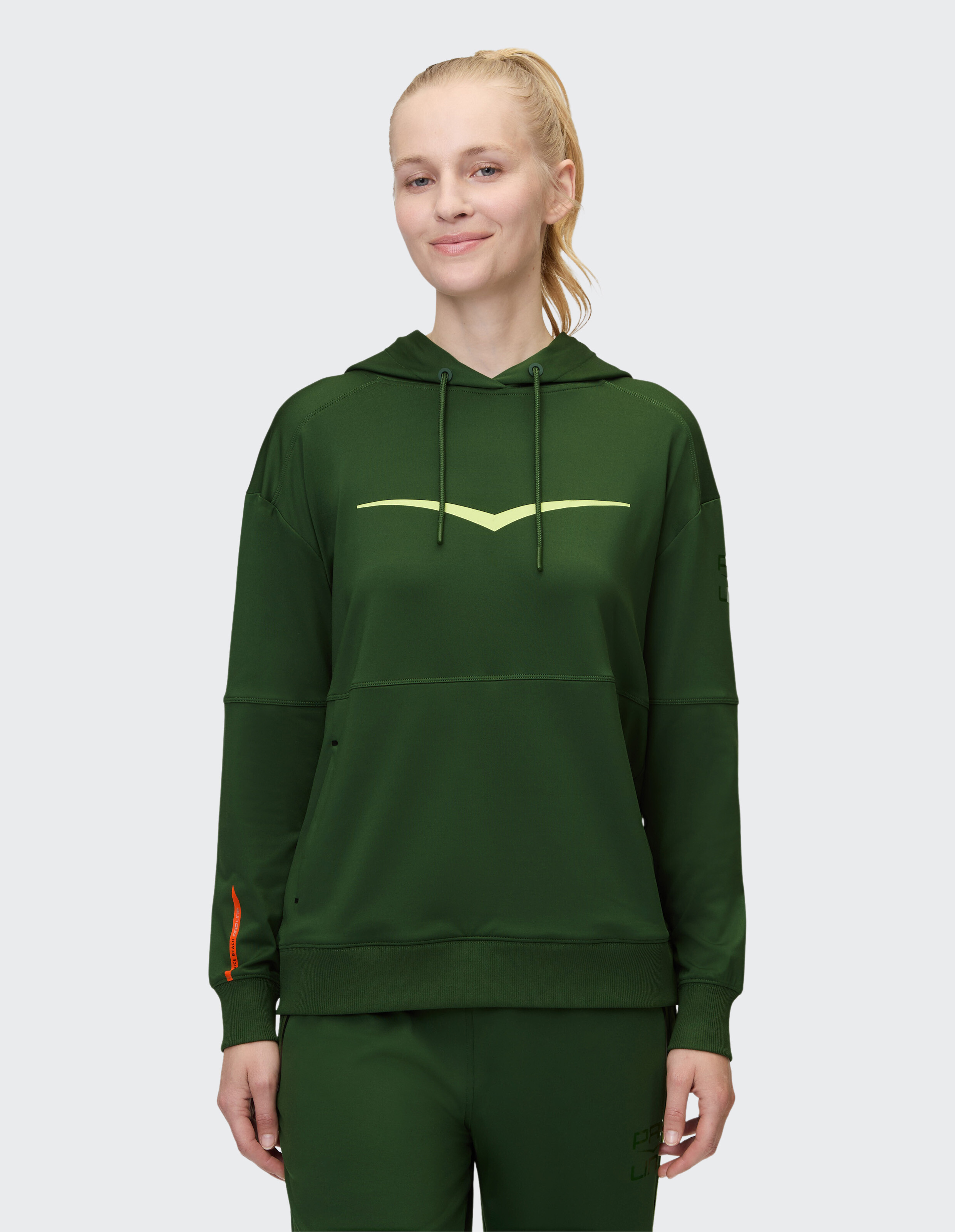 Frau trägt einen kuscheligen dunkelgrünen ELBSAND-Hoodie mit gelbem Grafikdruck.