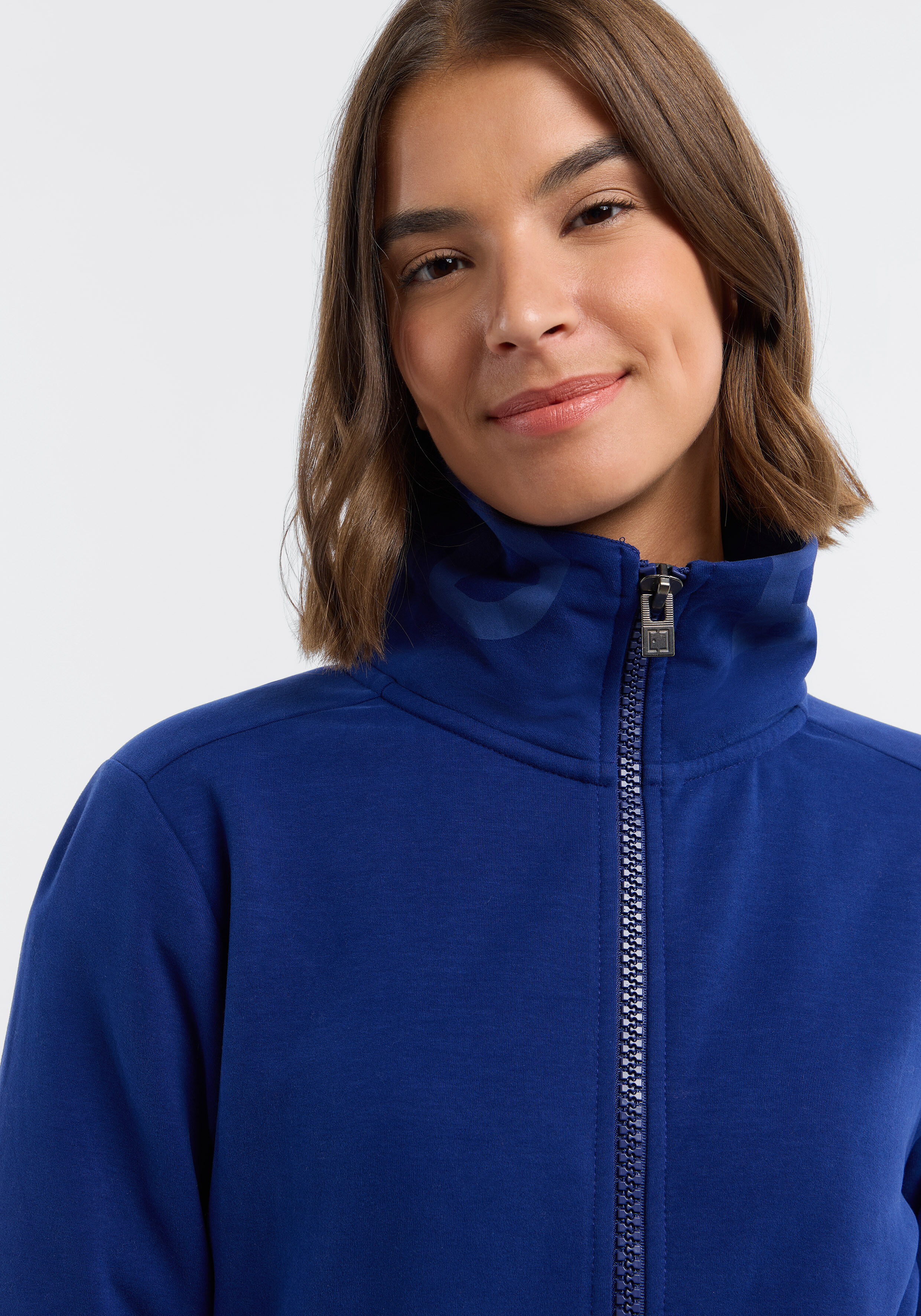 Frau trägt ein gemütliches blaues Sweatshirt mit Reißverschluss und hohem Kragen für lässigen Stil.