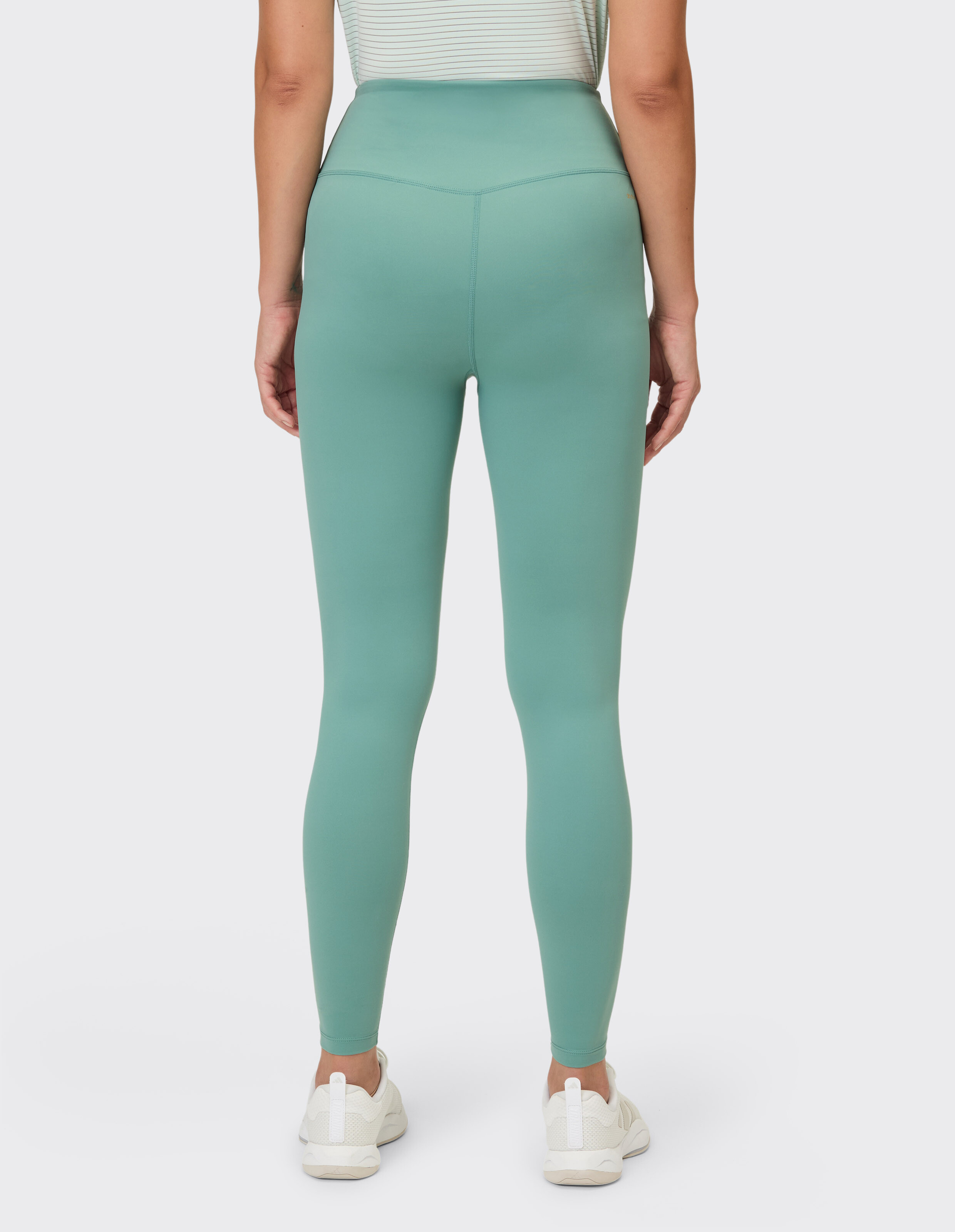 Rückansicht einer Frau, die salbeigrüne Leggings mit hoher Taille für lässigen Komfort trägt.
